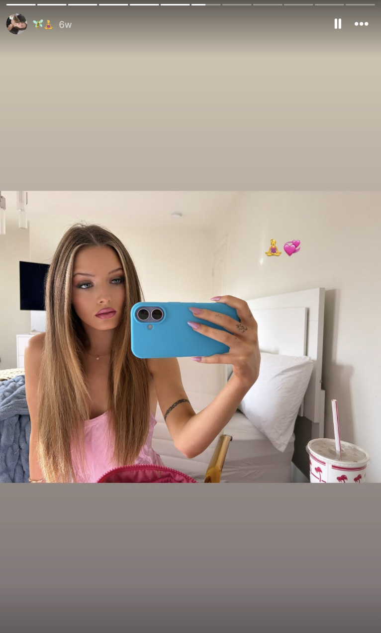 Harper Lockwood macht ein Spiegel-Selfie, während sie in ihrem Schlafzimmer sitzt. Sie hält eine leuchtend türkisfarbene Handyhülle in der Hand und trägt ein hellrosa Top, wobei ihr glattes, gesträhntes Haar ihr über die Schultern fällt. | Quelle: Instagram/harper.lockwoodd