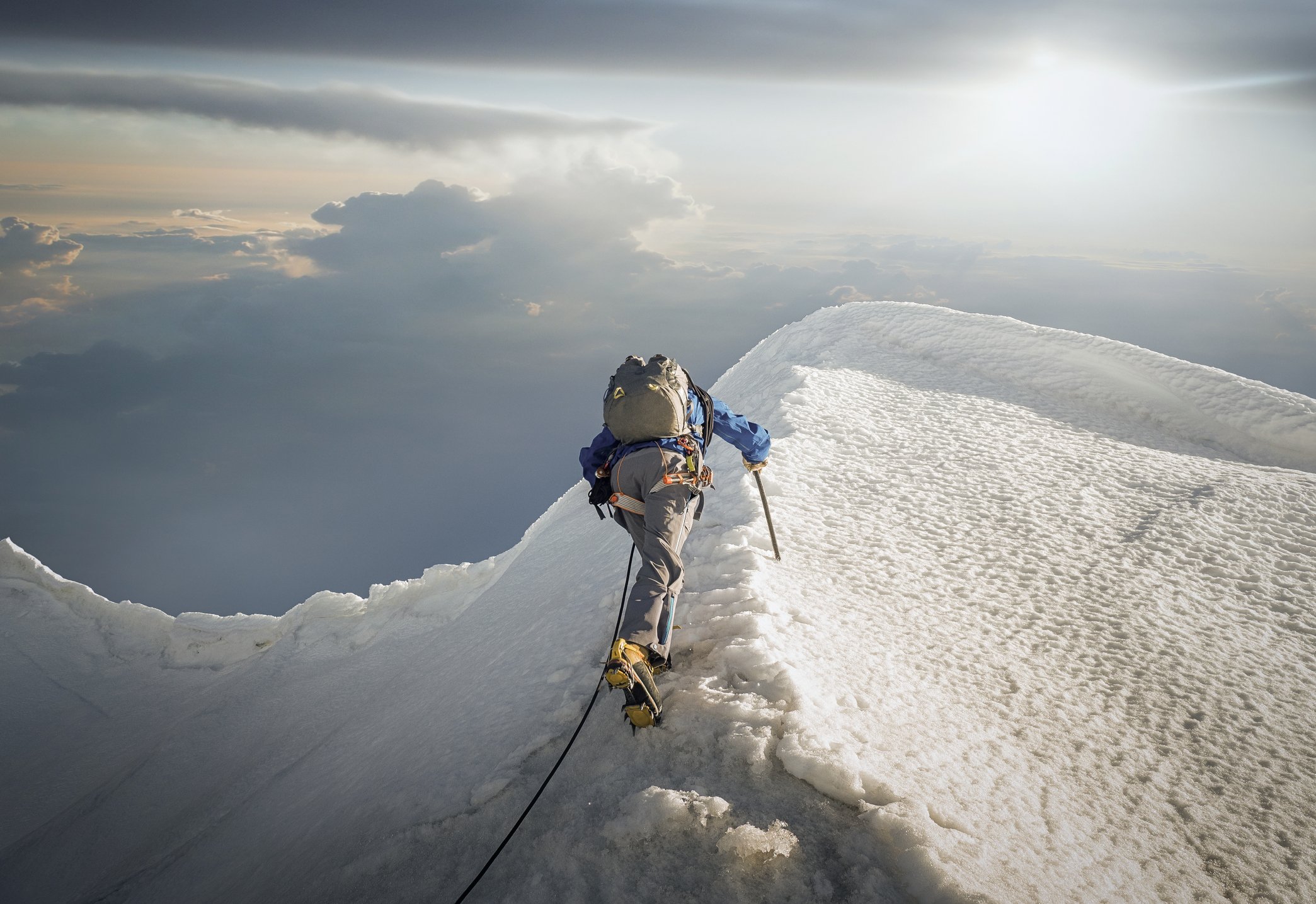 Ein einsamer Kletterer, der einen schneebedeckten Kamm in den Alpen hinaufsteigt | Quelle: Getty Images