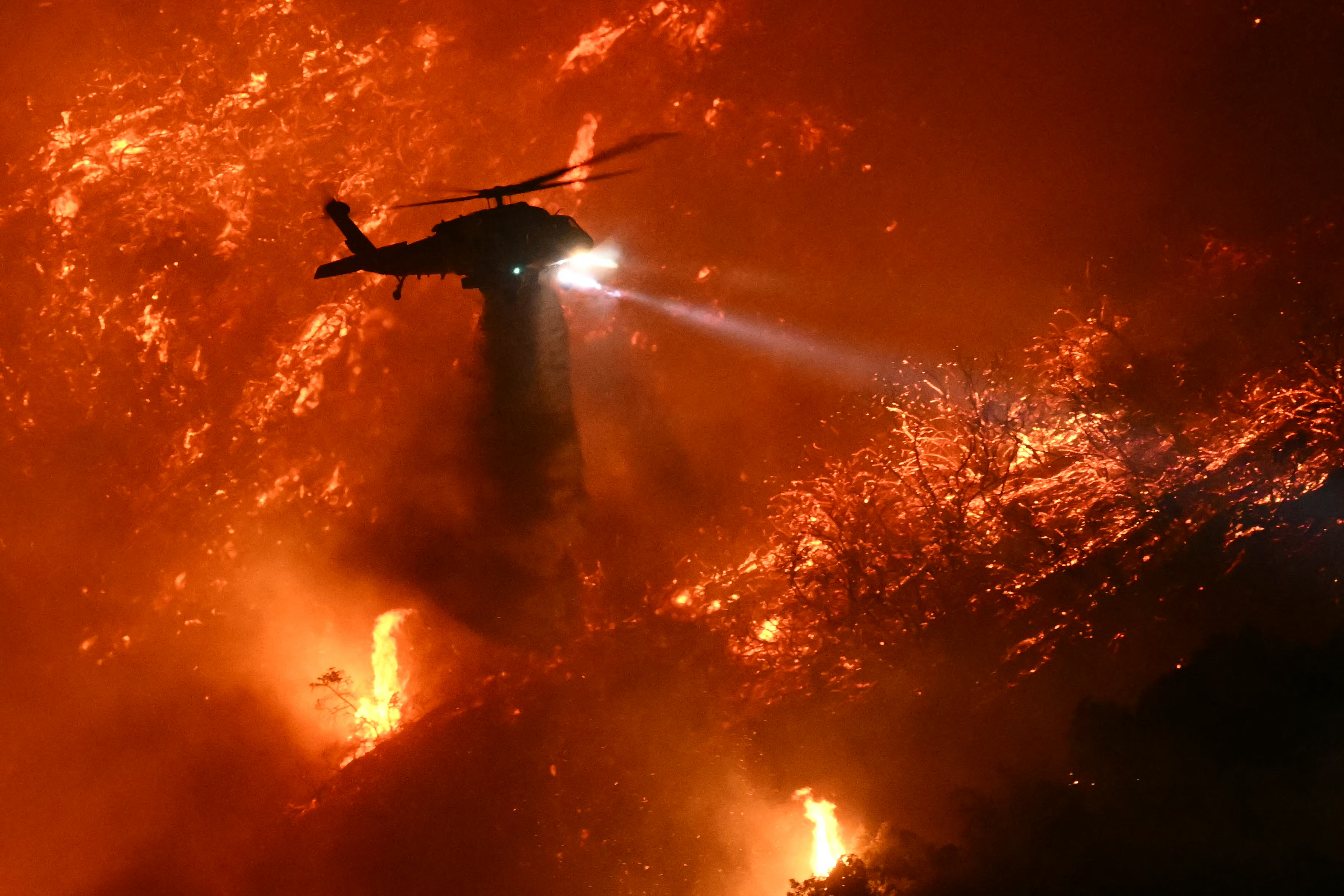 Ein Löschhubschrauber wirft Wasser ab, während das Palisades-Feuer in der Nähe des Mandeville Canyon-Viertels und Encino, Kalifornien, am 11. Januar 2025 wächst | Quelle: Getty Images