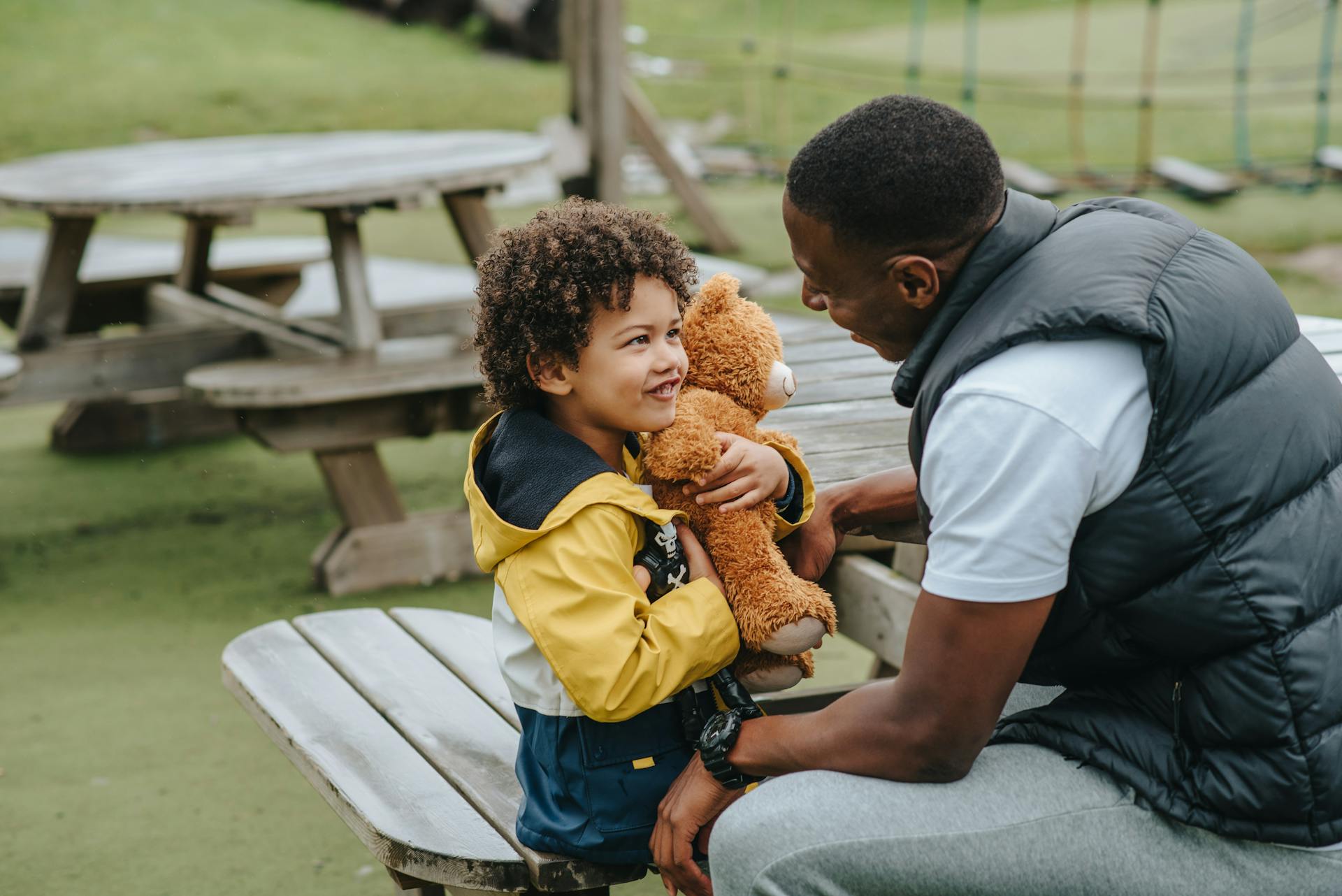 Ein Vater im Gespräch mit seinem kleinen Sohn auf dem Spielplatz | Quelle: Pexels