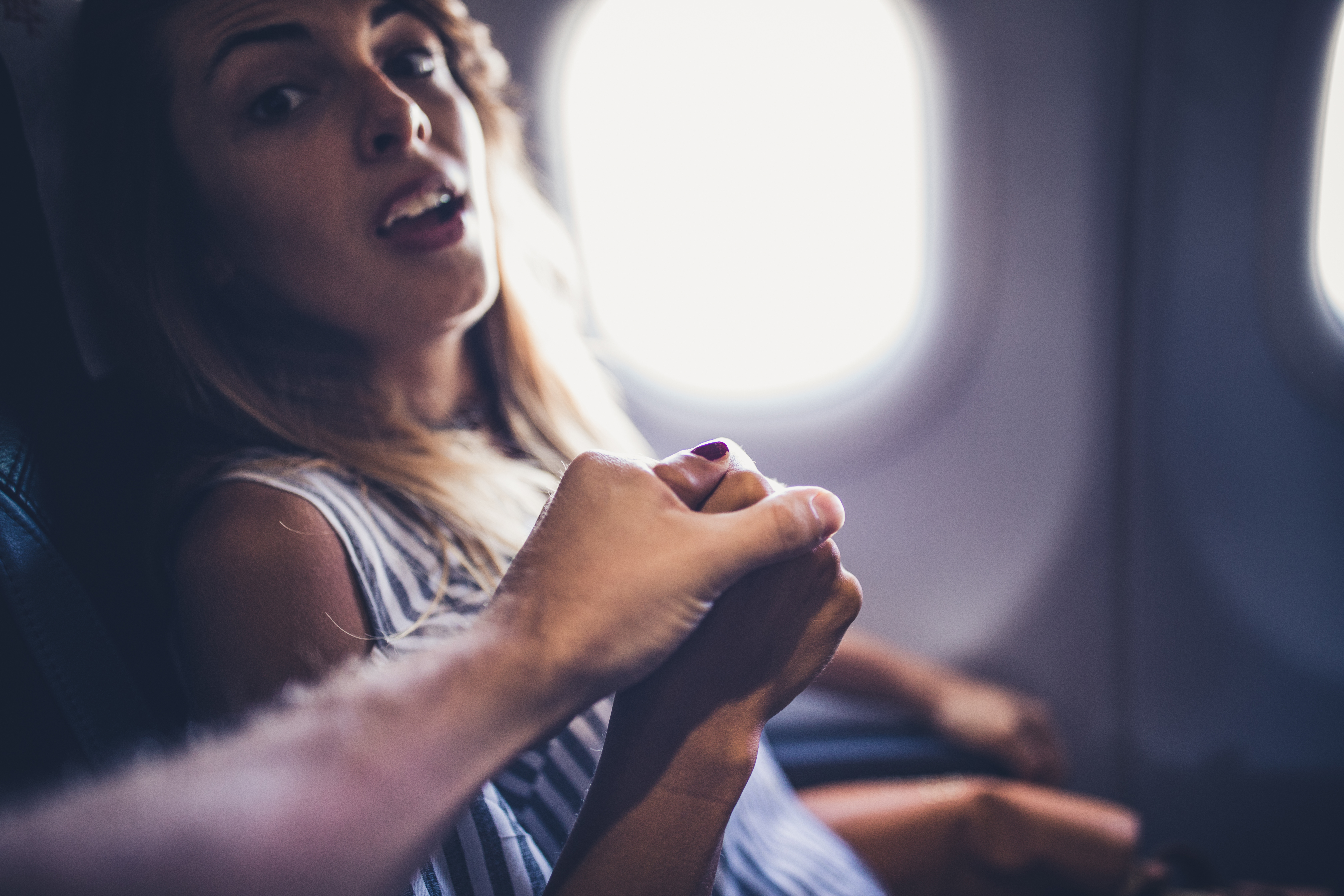 Ehemann hält die Hand seiner verängstigten Frau in einem Flugzeug | Quelle: Getty Images