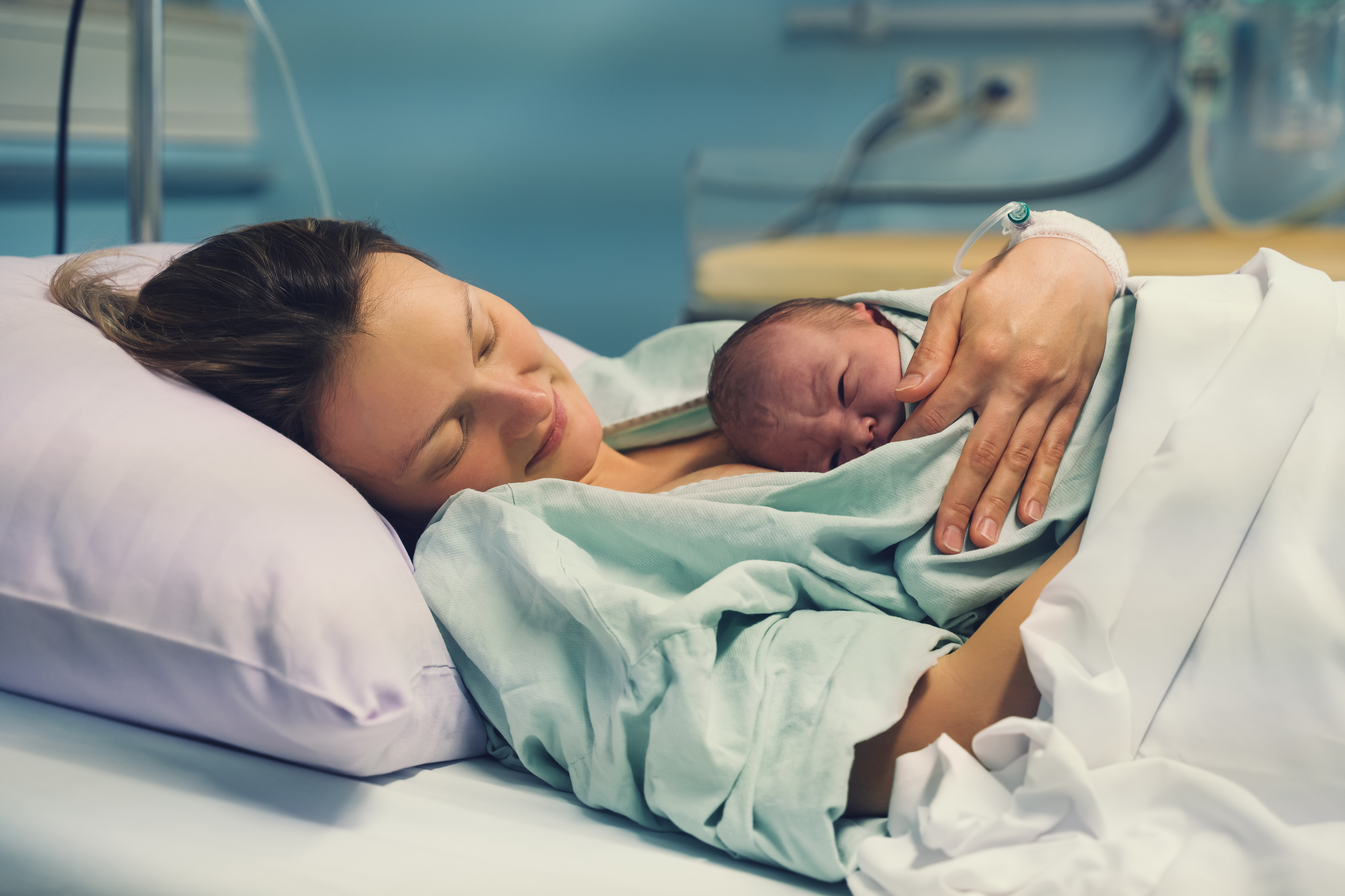 Frau und hält ihr Neugeborenes leidenschaftlich im Arm. | Quelle: Shutterstock