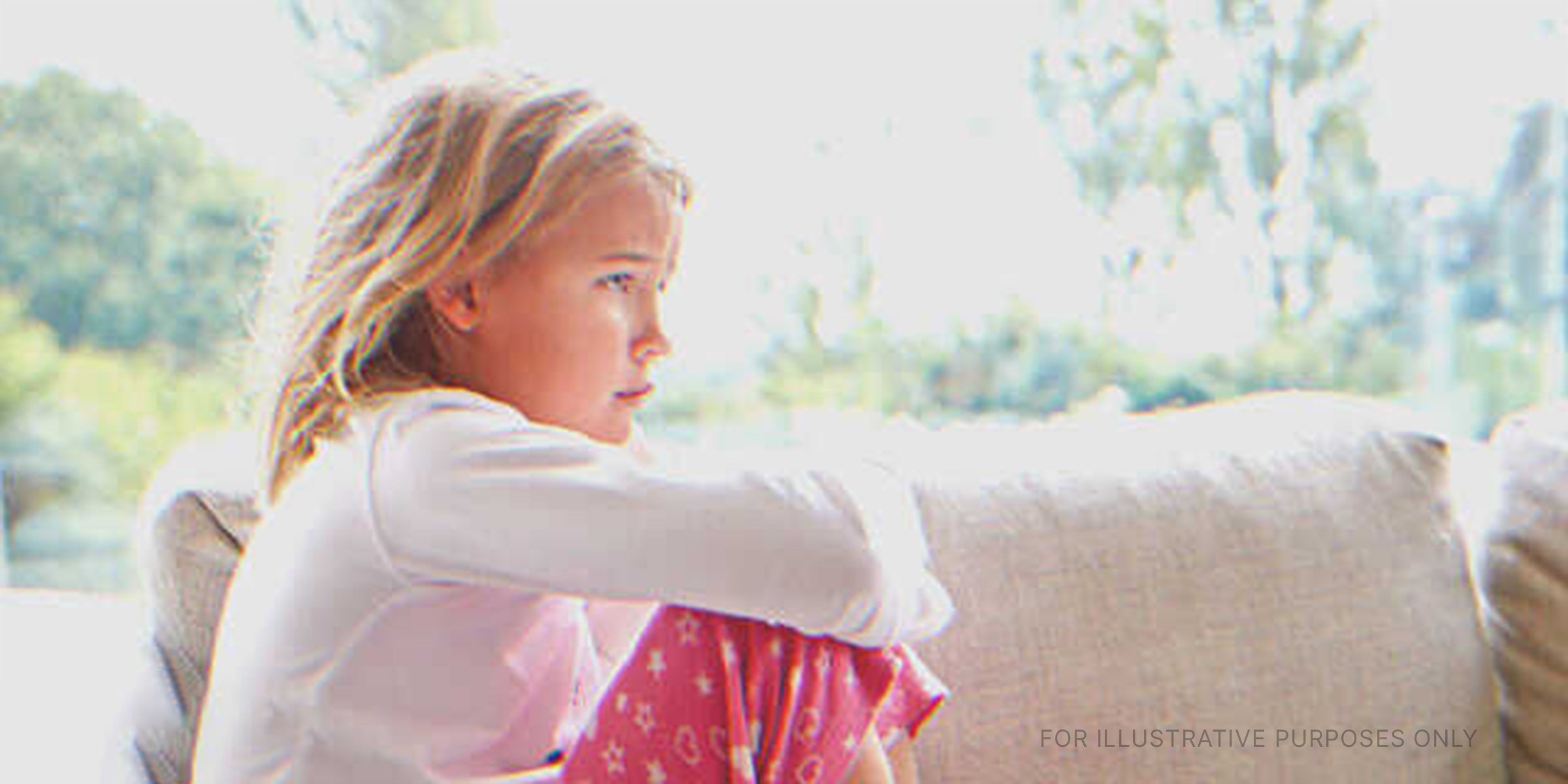 Trauriges kleines Mädchen, das auf der Couch sitzt. | Quelle: Shutterstock