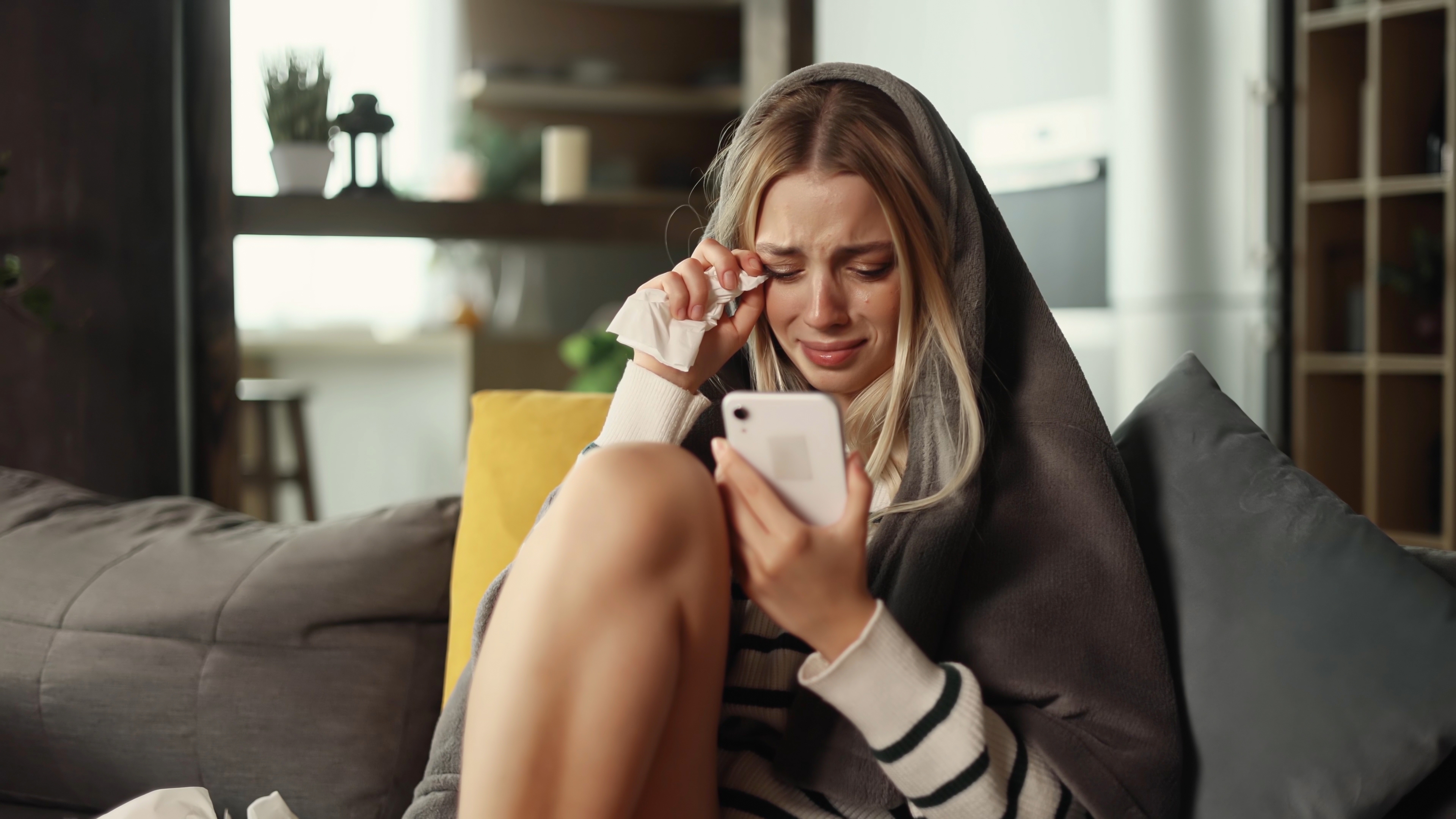 Junge Frau weint, während sie ihr Telefon benutzt | Quelle: Shutterstock