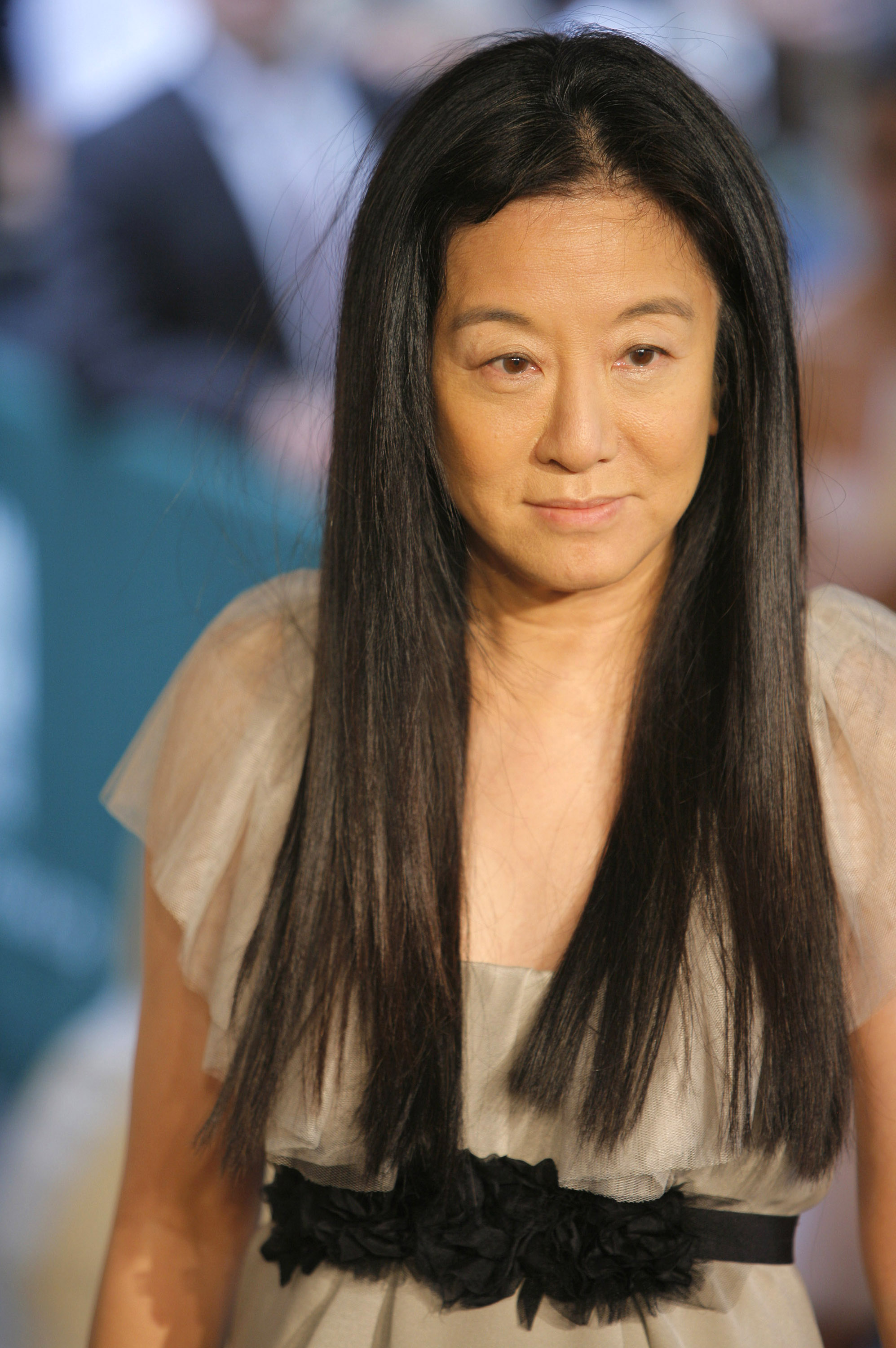 Die Modedesignerin Vera Wang posierte auf dem roten Teppich bei der Ankunft zu den CFDA Awards 2006 in New York City. Sie trug ein luftiges, dezentes taupefarbenes Abendkleid, das durch flatternde Tüll-Flügelärmel und einen kontrastierenden schwarzen Blumenrosetten-Taillenbund akzentuiert wurde, während sie ihr charakteristisches rabenschwarzes Haar glatt und mit Mittelscheitel trug. | Quelle: Getty Images
