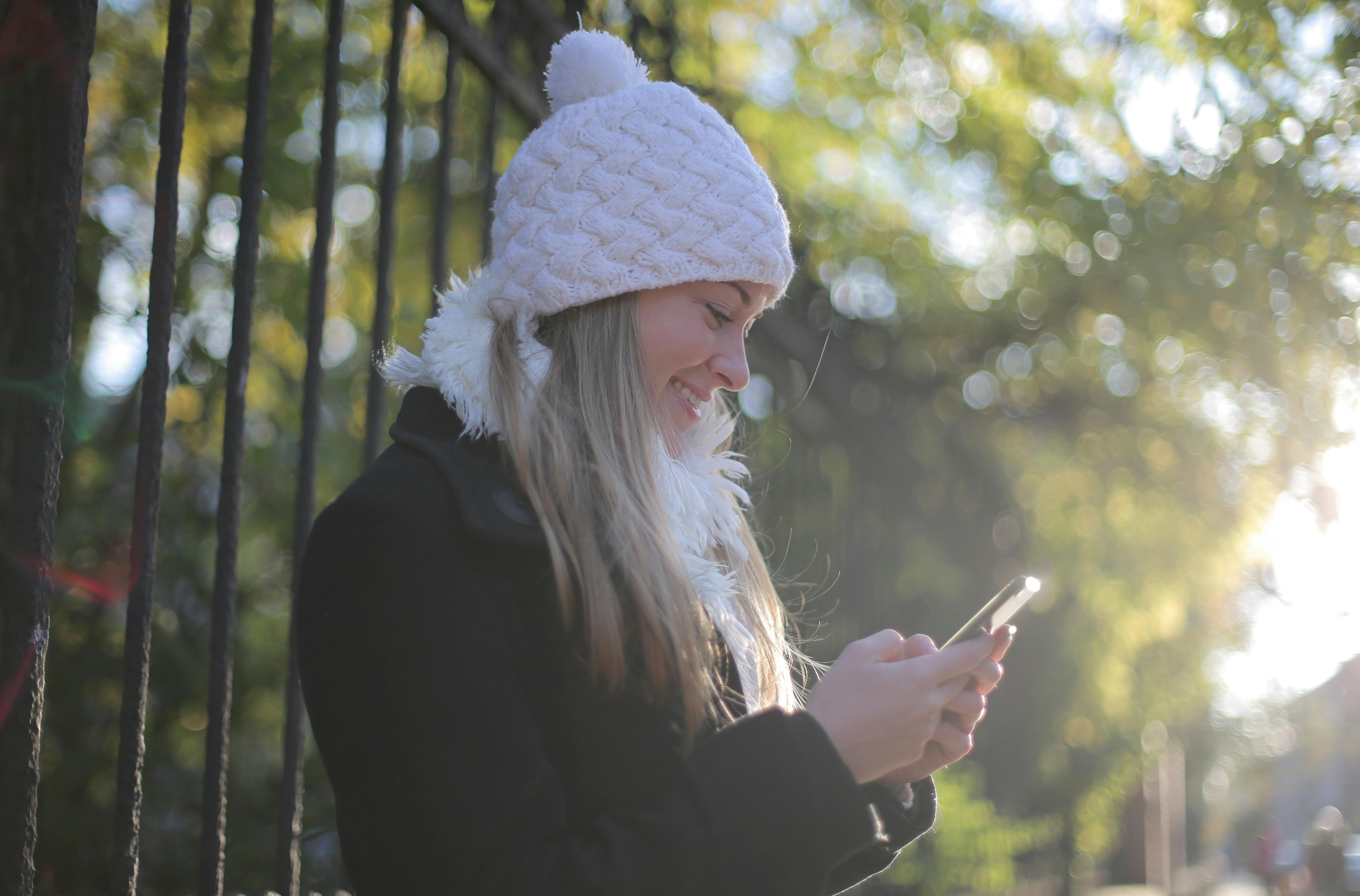 Eine Frau lächelt, während sie auf ihr Telefon schaut | Quelle: Pexels