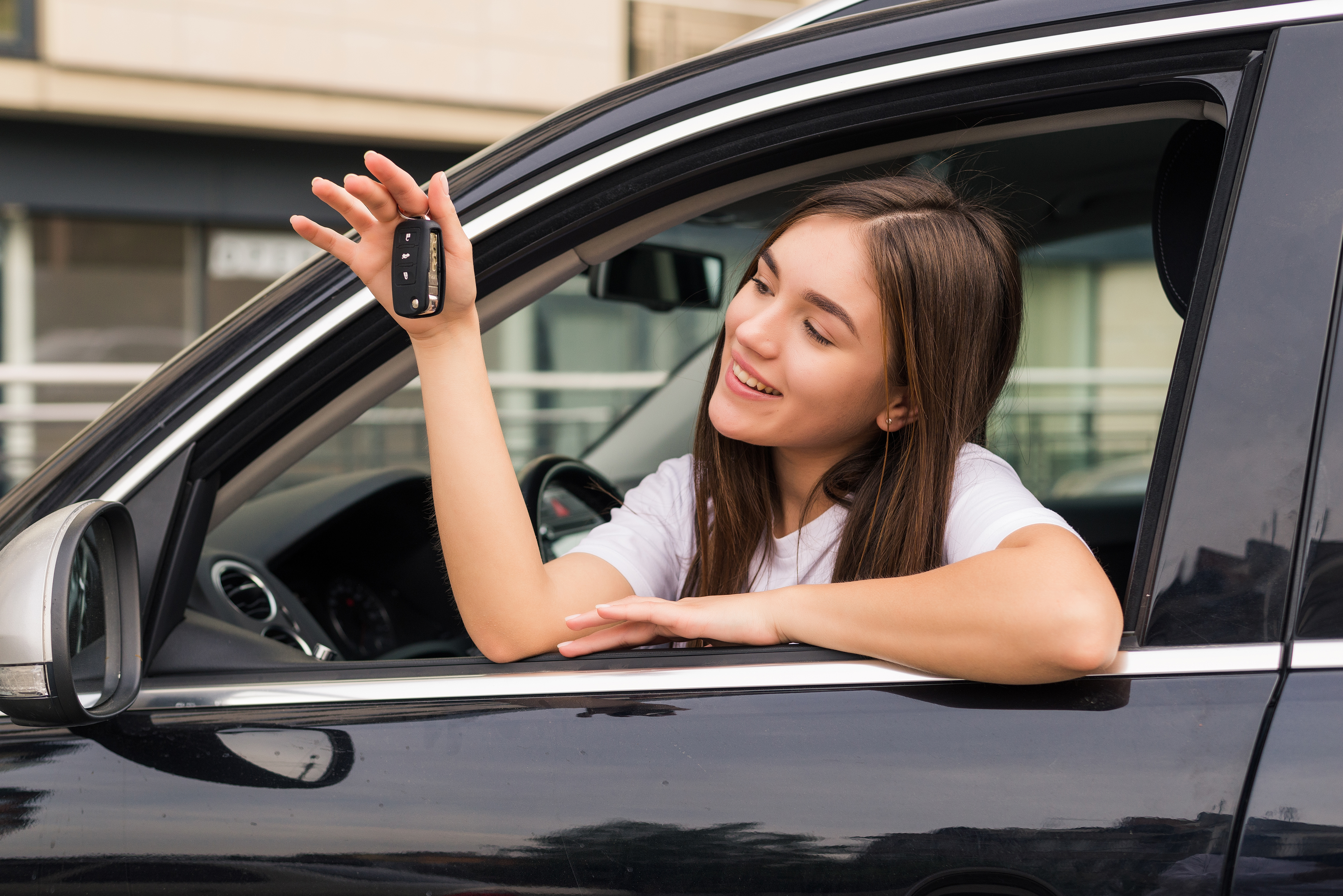 Glückliches junges Mädchen in einem Auto, während sie ihre Autoschlüssel hochhält | Quelle: Freepik
