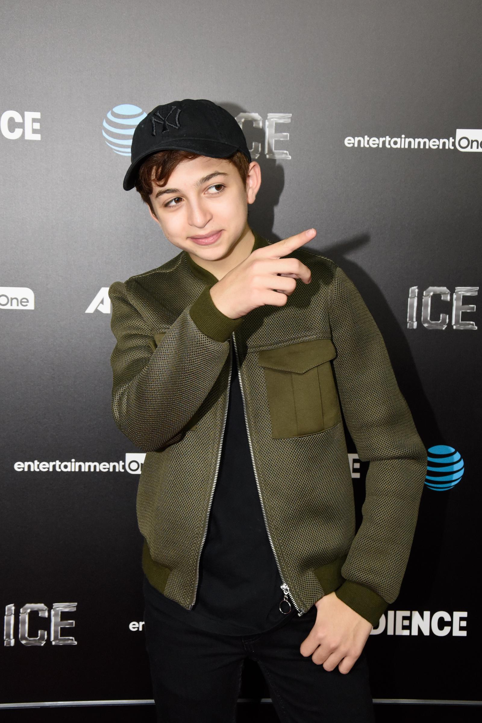 J.J. Totah kommt zur Premiere von „Ice“ des Audience Network im ArcLight Cinemas in Hollywood, Kalifornien, und trägt dabei eine olivgrüne, strukturierte Jacke, eine schwarze Baseballkappe und eine dunkle Hose. Totah zeigt zur Seite, während er für die Fotografen posiert. | Quelle: Getty Images