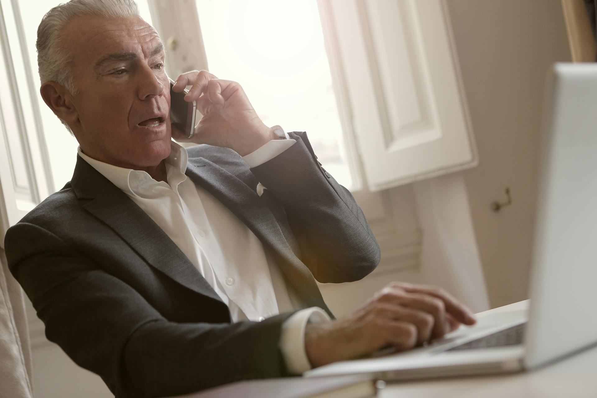 Ein besorgter Mann telefoniert, während er seinen Laptop benutzt | Quelle: Pexels