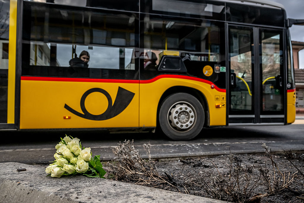 Ein Postbus fährt am 11. März 2026 in Kerzers in der Westschweiz an Blumen vorbei, einen Tag nachdem ein Bus desselben öffentlichen Unternehmens am 10. März 2026 in Brand geraten war. Dabei kamen mindestens sechs Menschen ums Leben und fünf weitere wurden verletzt. Nach Angaben der Polizei könnte es sich um eine vorsätzliche Tat handeln. | Quelle: Getty Images