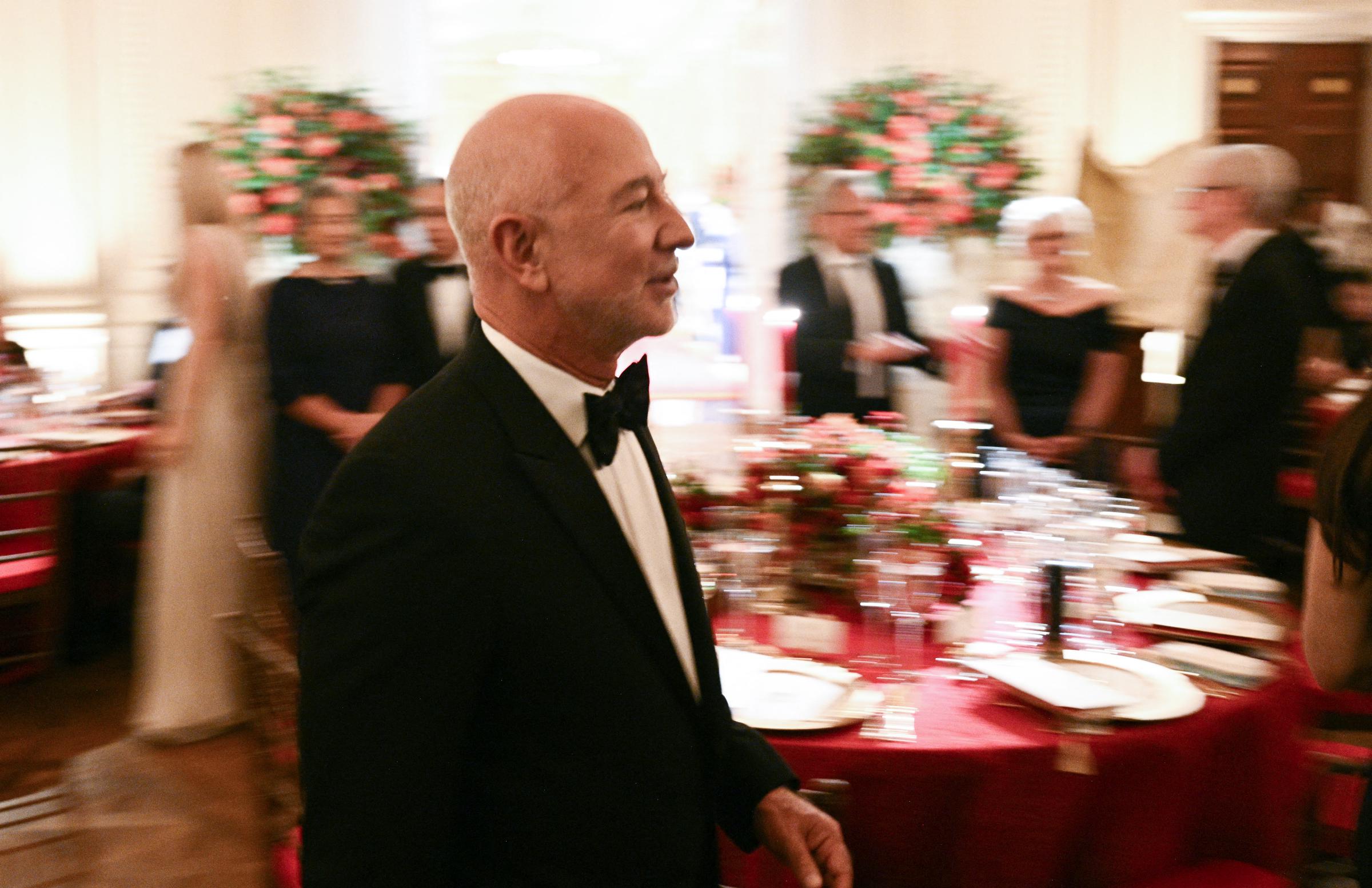Jeff Bezos bewegte sich am 24. September 2026 in Washington, D.C., beim Staatsbankett zu Ehren des chinesischen Präsidenten Xi Jinping in einem klassischen schwarzen Smoking und mit Fliege durch den belebten East Room des Weißen Hauses. Auf einer dynamischen Schnappschussaufnahme, die ihn an den mit leuchtend roten Tischdecken und Blumengestecken geschmückten Banketttischen vorbeigehen zeigt, gesellte sich der Amazon-Gründer zu anderen prominenten Wirtschaftsführern und Würdenträgern, die sich zu den diplomatischen Feierlichkeiten des Abends versammelt hatten. | Quelle: Getty Images
