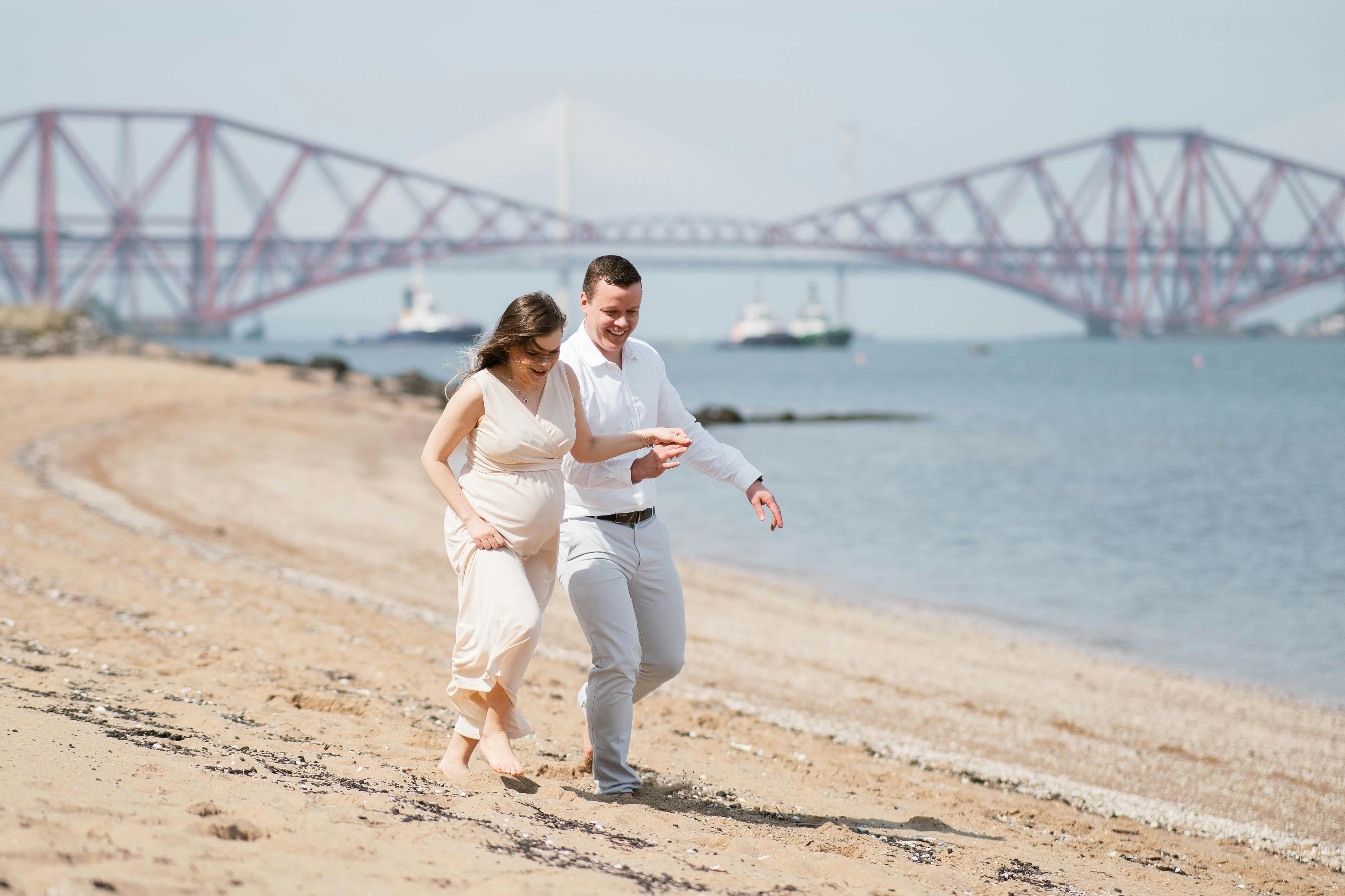 Eine schwangere Frau und ihr Partner gehen an einem Strand entlang | Quelle: Pexels