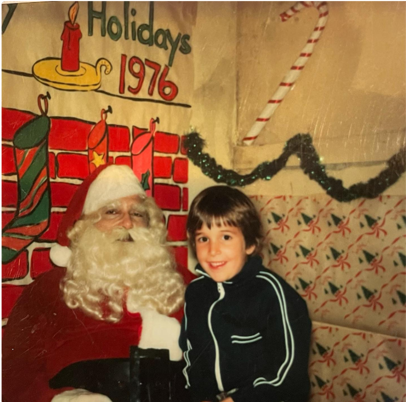 Der Schauspieler, damals noch ein kleiner Junge, lächelt 1976 bei einer Weihnachtsfeier neben einer Person, die als Weihnachtsmann verkleidet ist – eine schöne Kindheitserinnerung. | Quelle: Instagram/therealnoahwyle