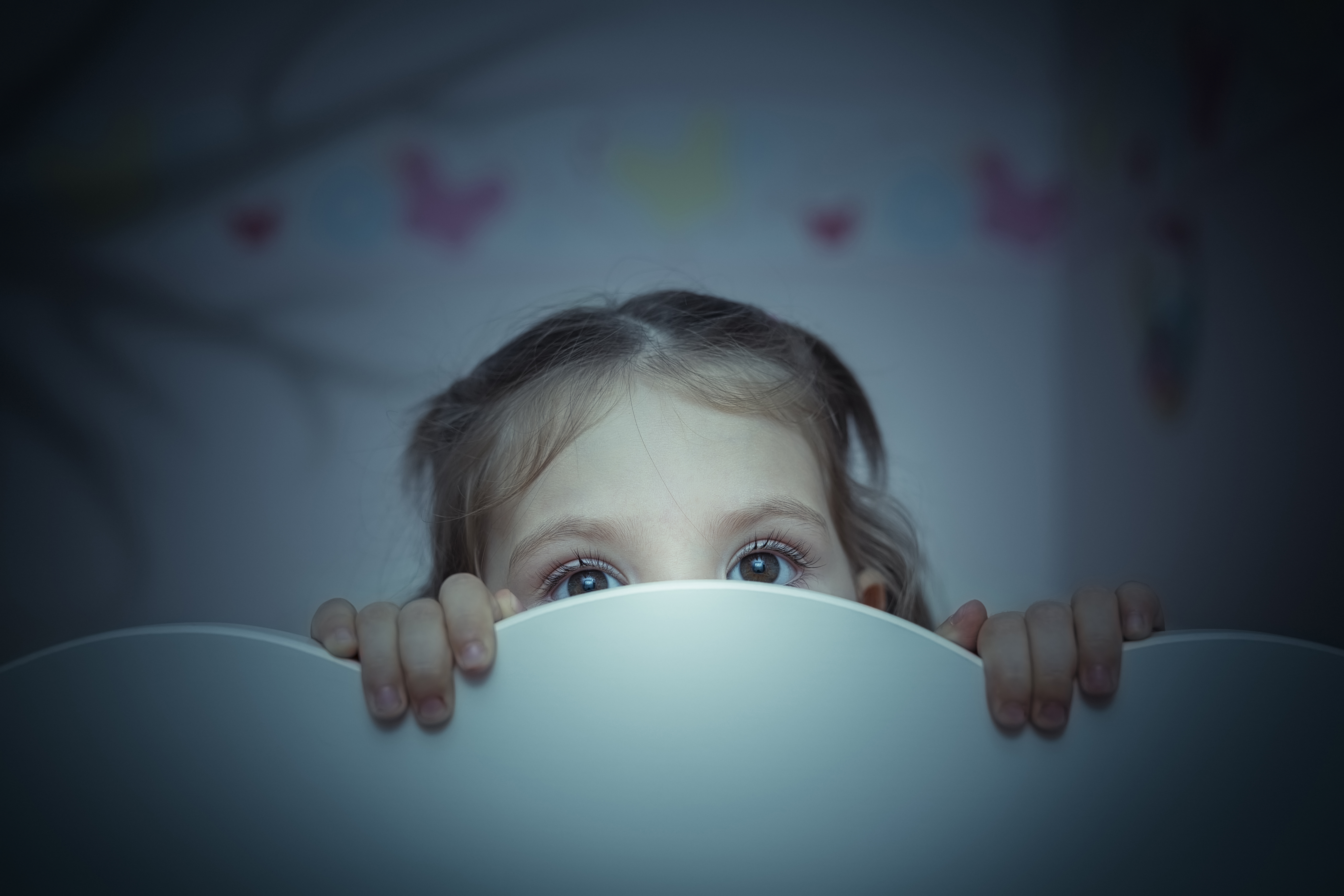 Ein kleines Mädchen versteckt sich hinter einer weißen Fläche | Quelle: Shutterstock