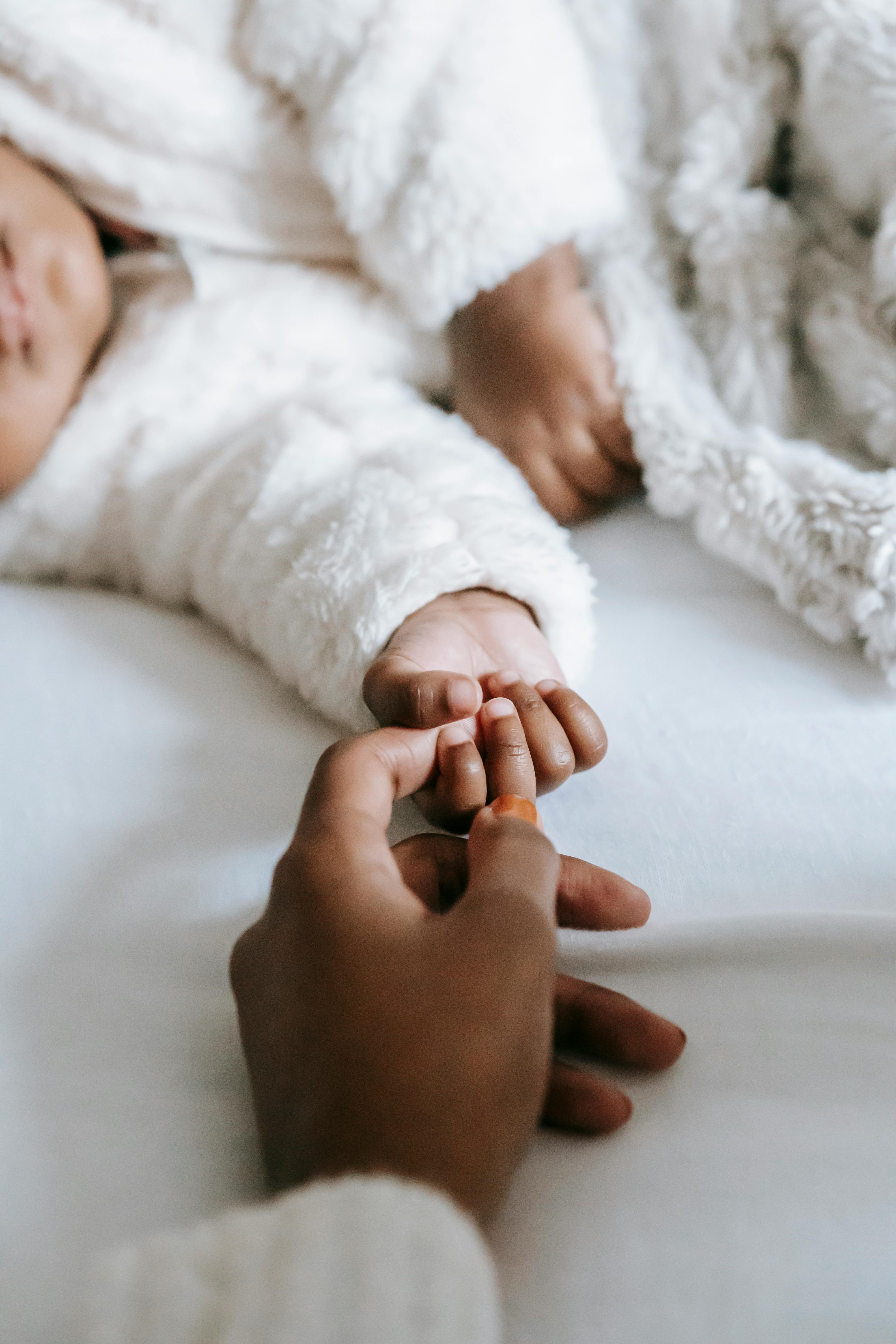 Die Hand einer Frau berührt die Hand eines Babys | Quelle: Pexels