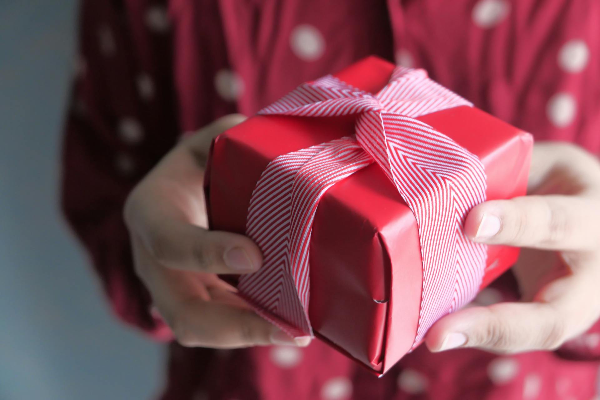 Eine Frau hält eine kleine als Geschenk verpackte Schachtel in die Höhe | Quelle: Pexels