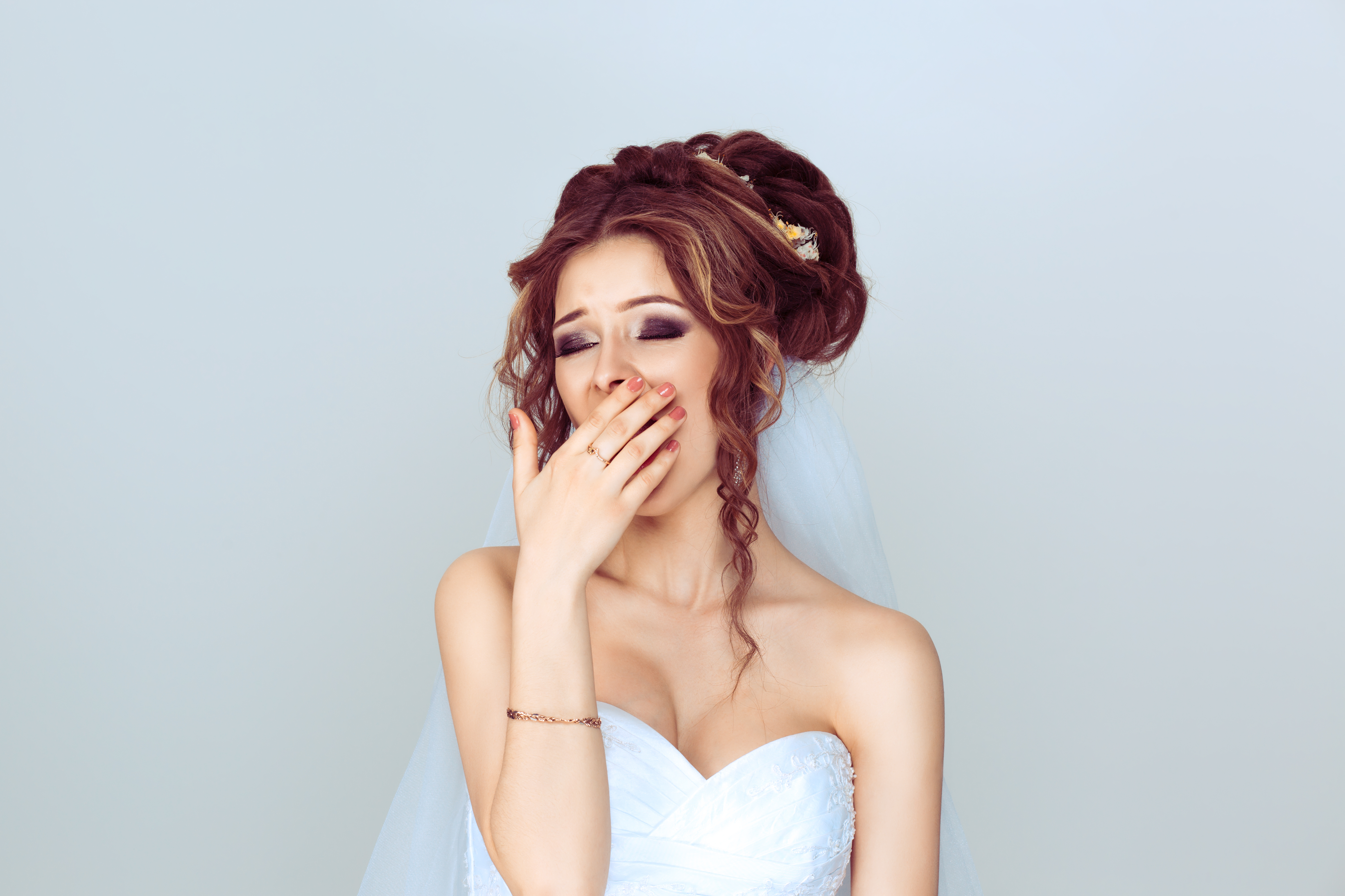Eine Braut hält sich den Mund zu, während sie gähnt | Quelle: Shutterstock