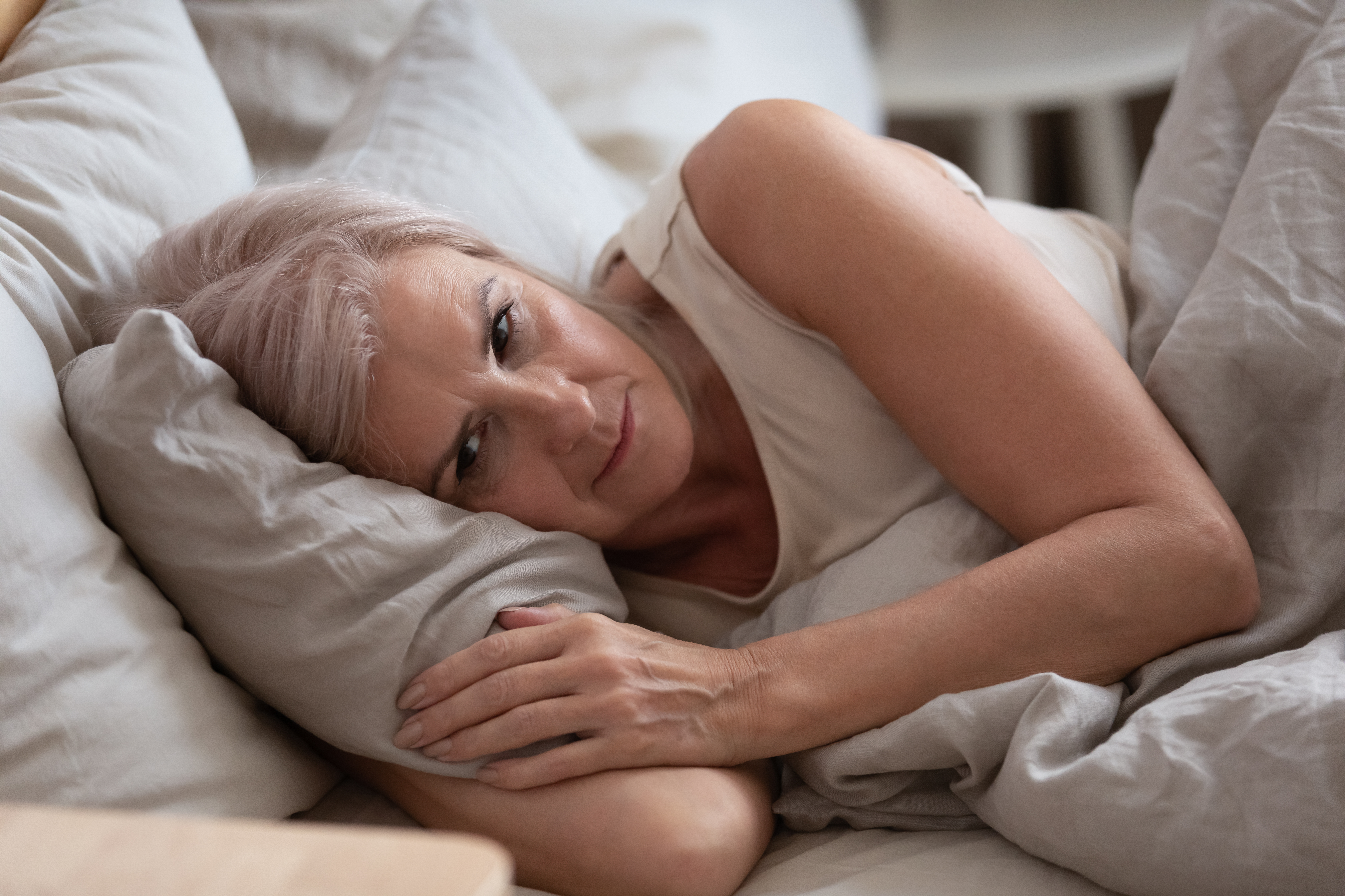 Eine Frau, die in Gedanken versunken im Bett liegt | Quelle: Shutterstock