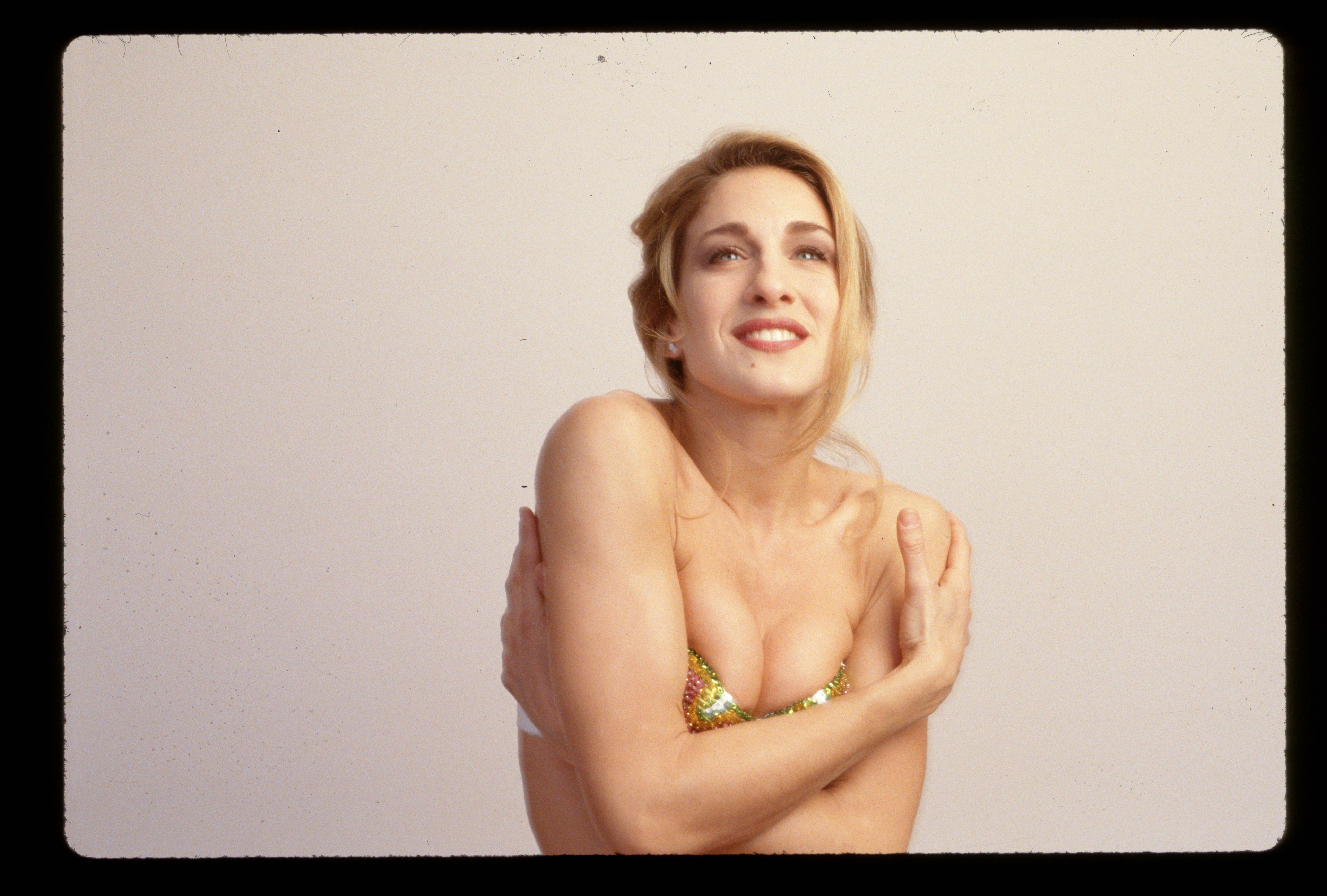 Sarah Jessica Parker ist 1990 in einem mit Pailletten besetzten Bikinioberteil mit vor der Taille verschränkten Armen zu sehen. | Quelle: Getty Images