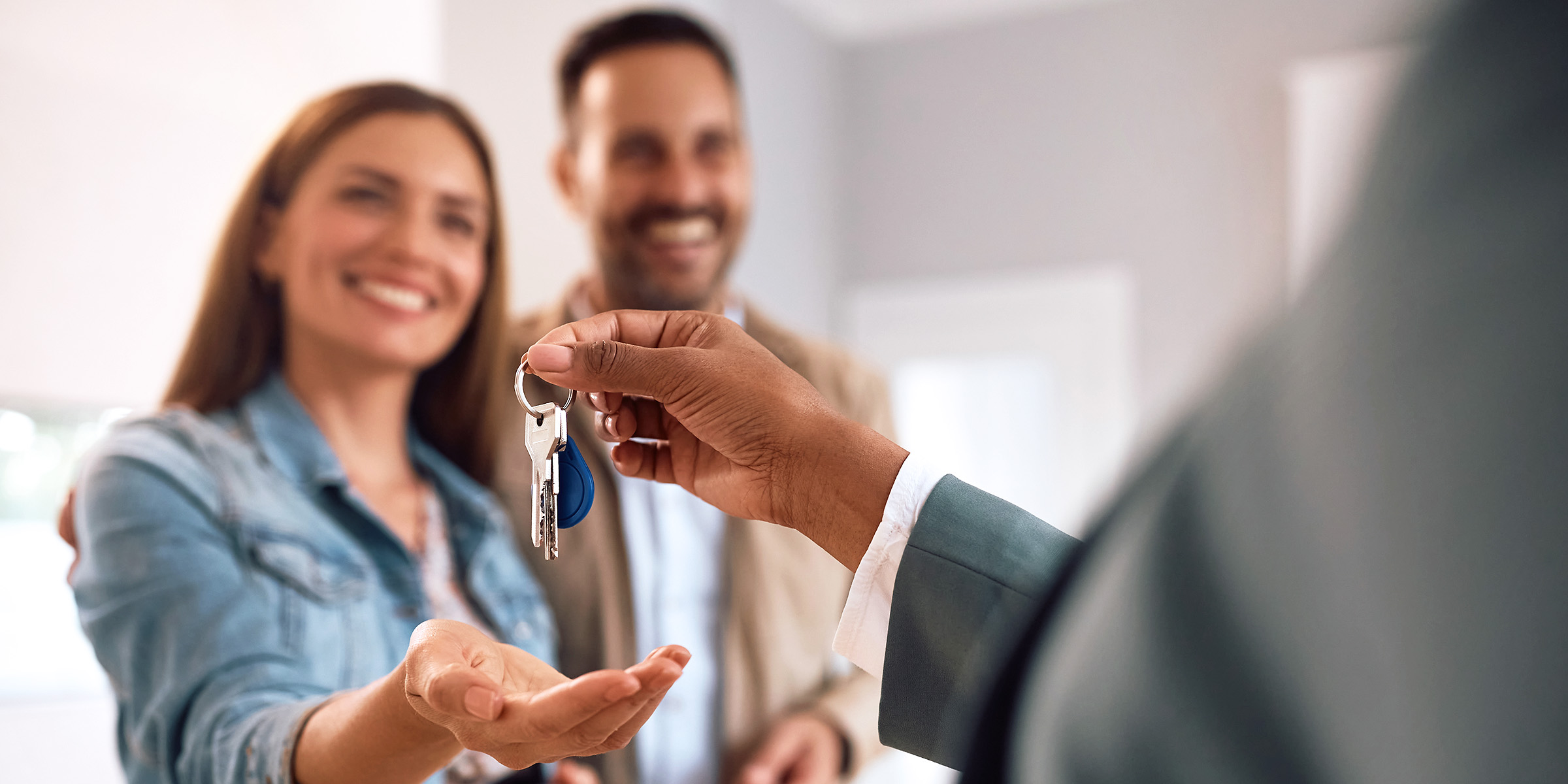 Ein glückliches Paar, das die Schlüssel für sein neues Haus entgegennimmt | Quelle: Shutterstock
