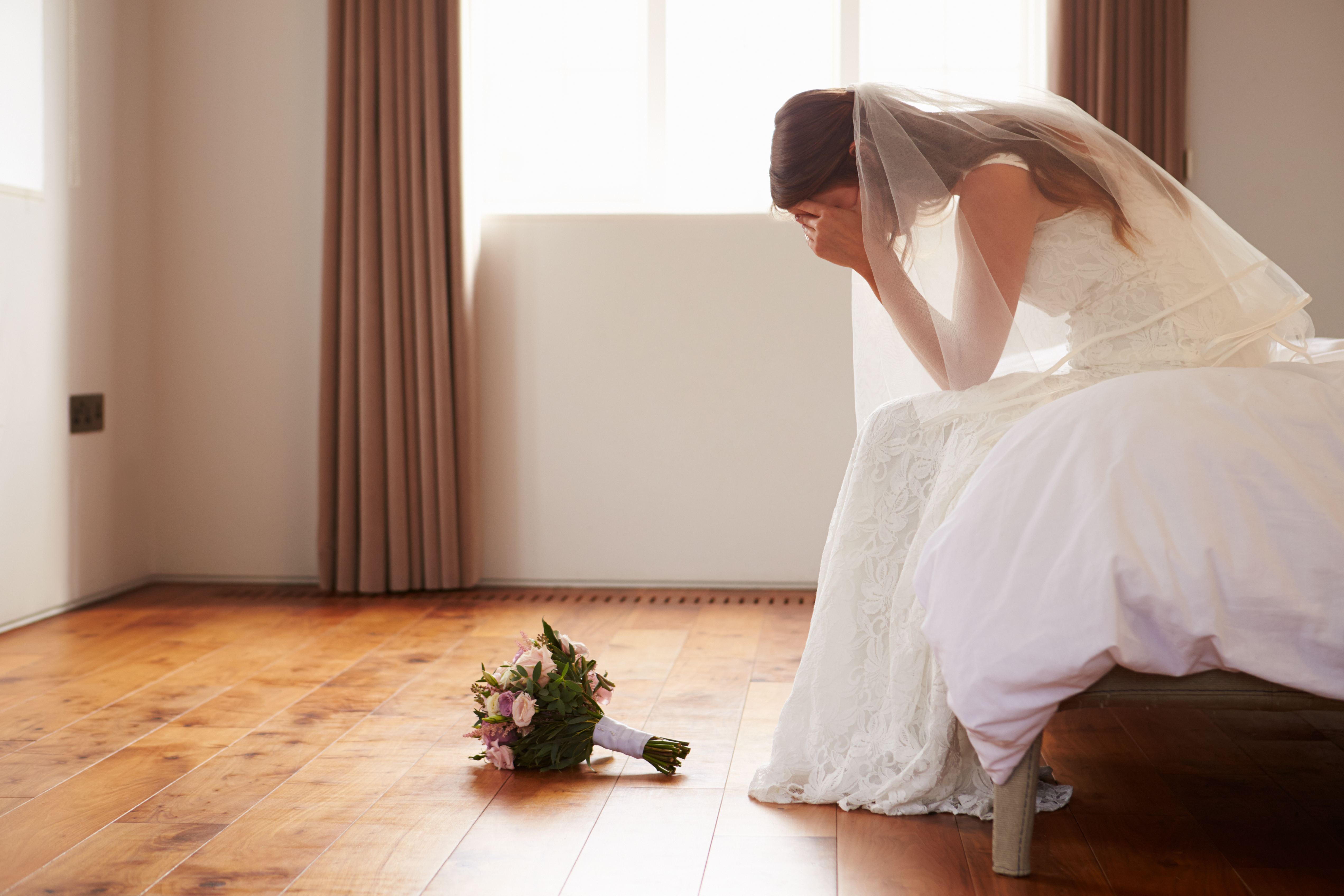 Eine traurige Braut sitzt in einem Zimmer | Quelle: Shutterstock