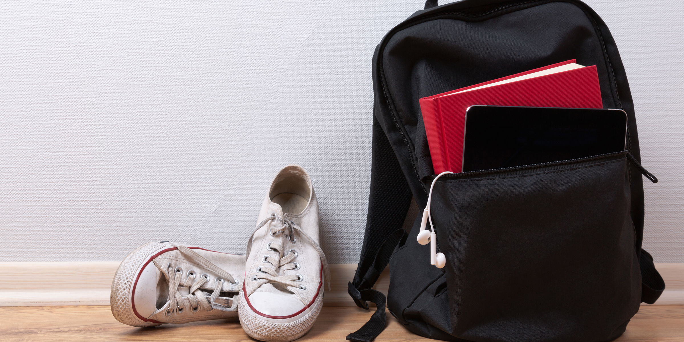 Ein schwarzer Rucksack neben einem Paar weißer Turnschuhe | Quelle: Shutterstock