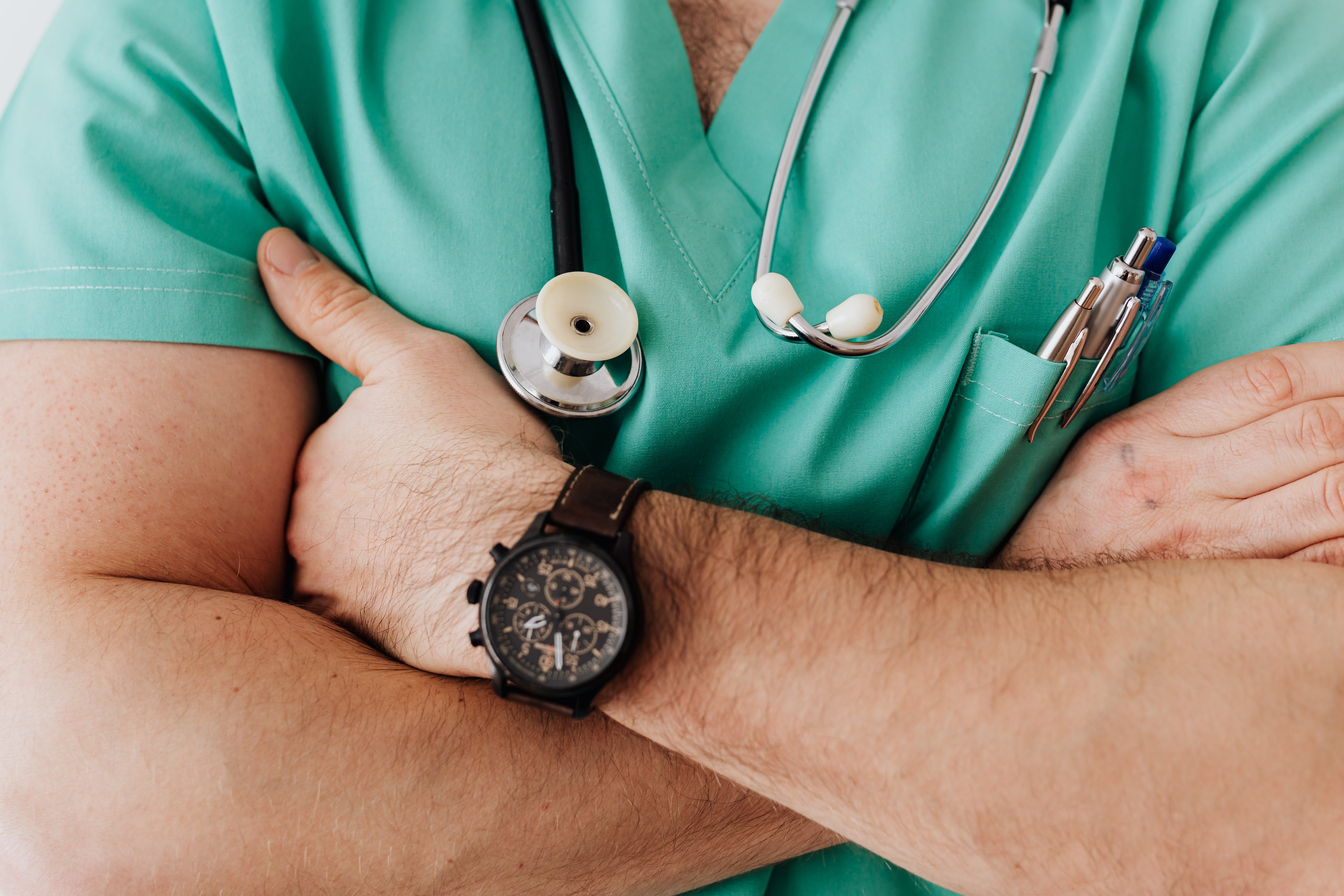 Ein praktizierender Arzt mit vor der Brust gefalteten Händen | Quelle: Pexels