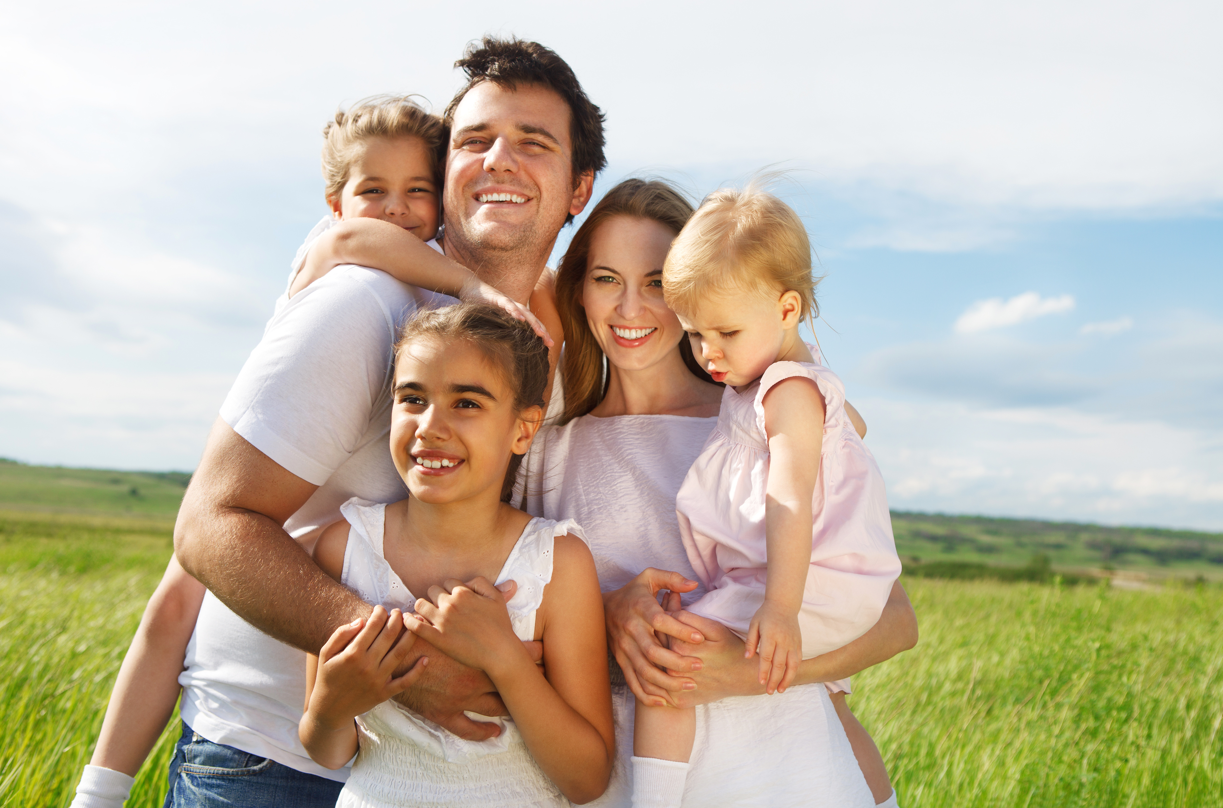 Glückliche Eltern mit drei Kindern im Freien | Quelle: Shutterstock