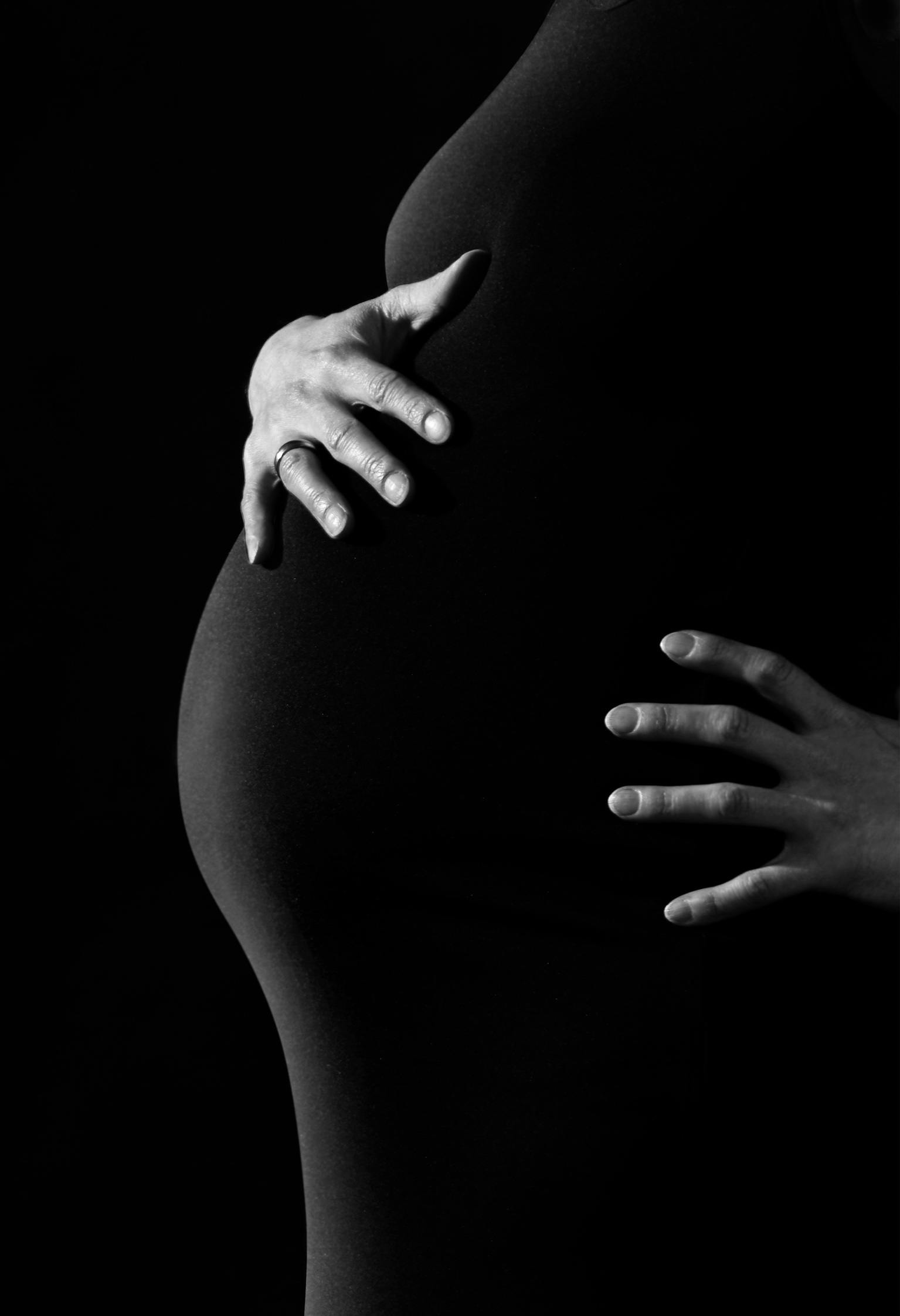 Ein Schwarz-Weiß-Foto von einer Frau, die ihren schwangeren Bauch hält | Quelle: Pixabay auf Pexels
