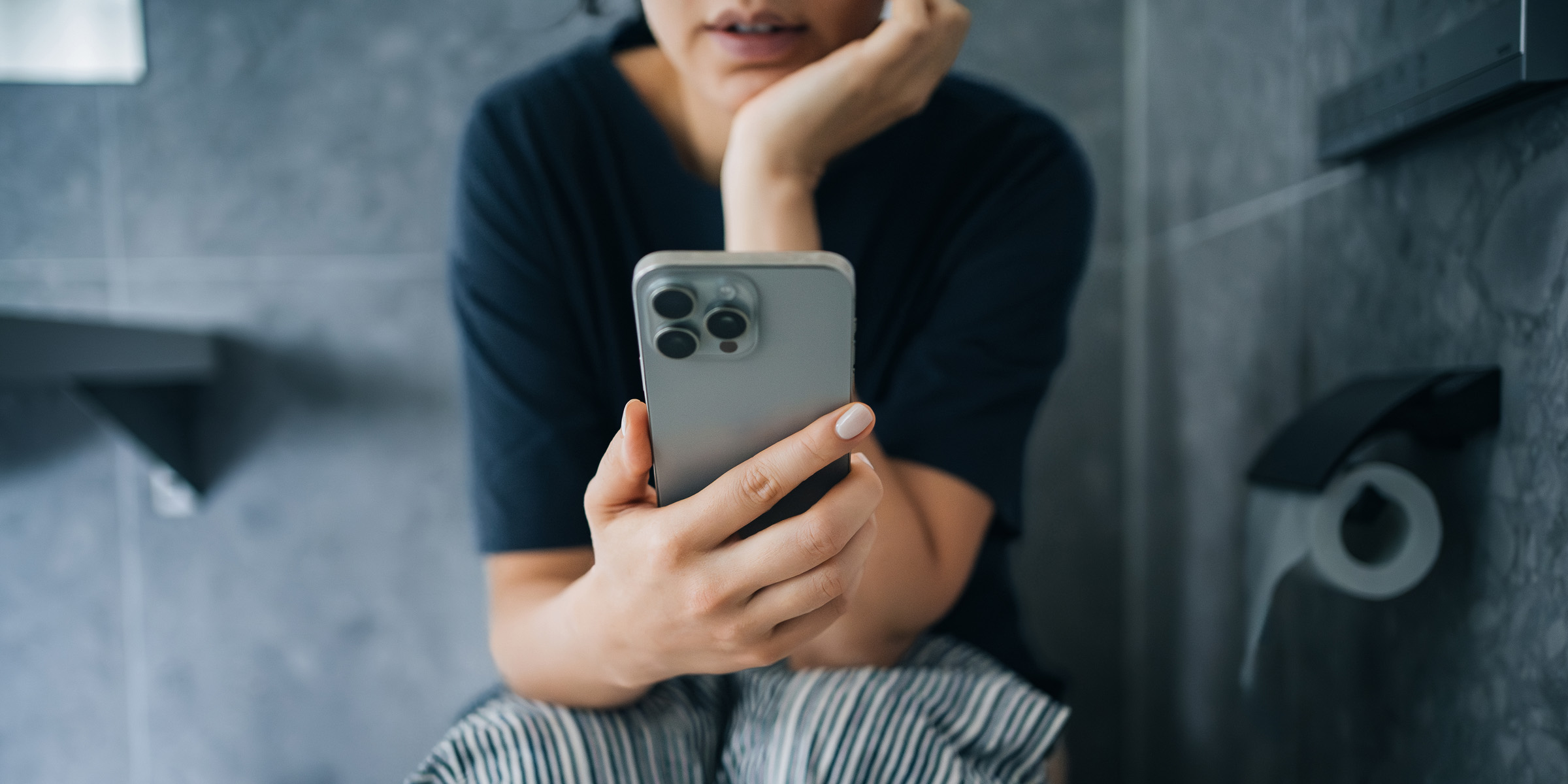 Eine Frau scrollt auf ihrem Handy, während sie auf der Toilette sitzt | Quelle: Getty Images
