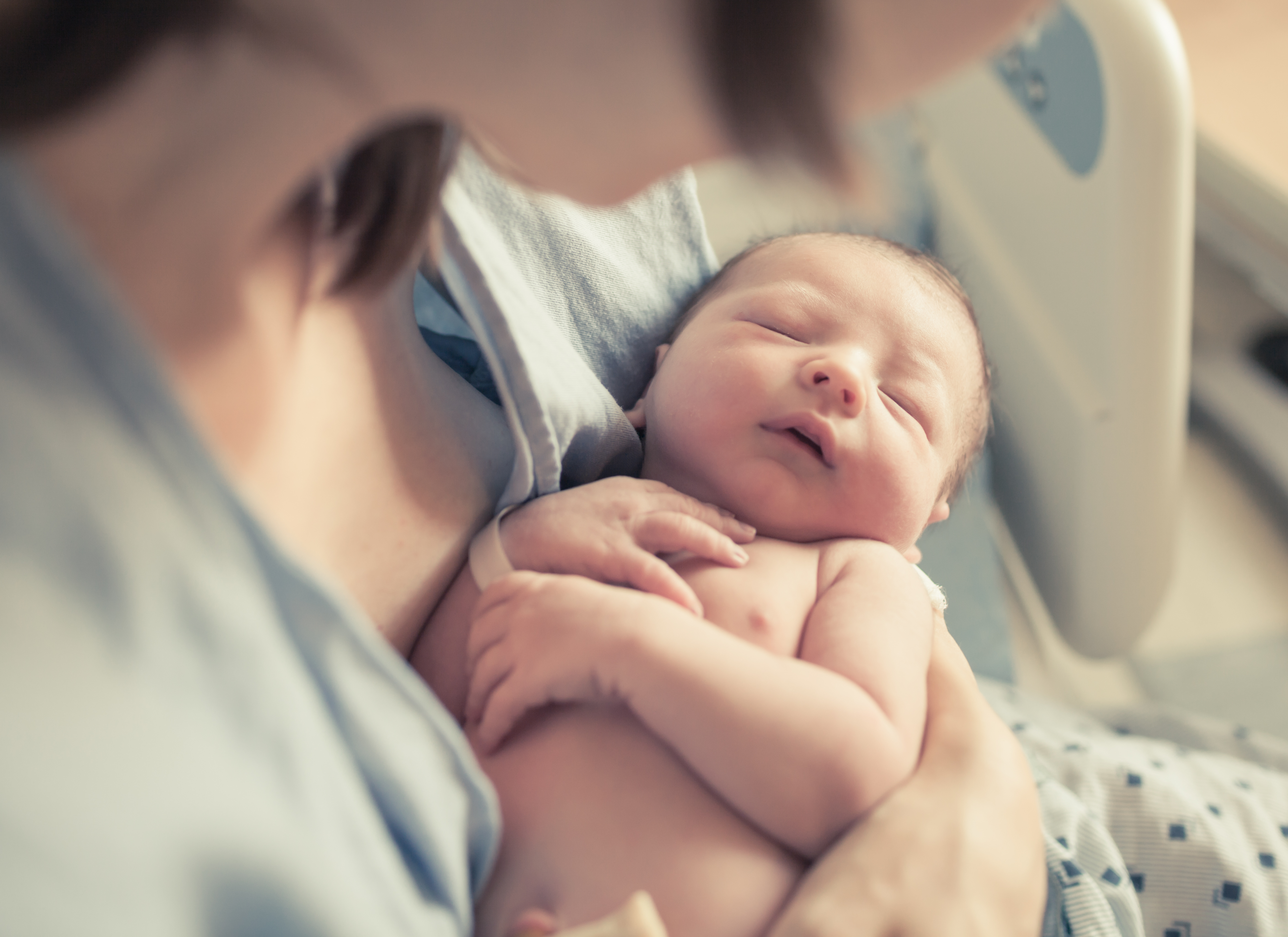 Eine Mutter, die ihr neugeborenes Baby in den Arm nimmt | Quelle: Shutterstock