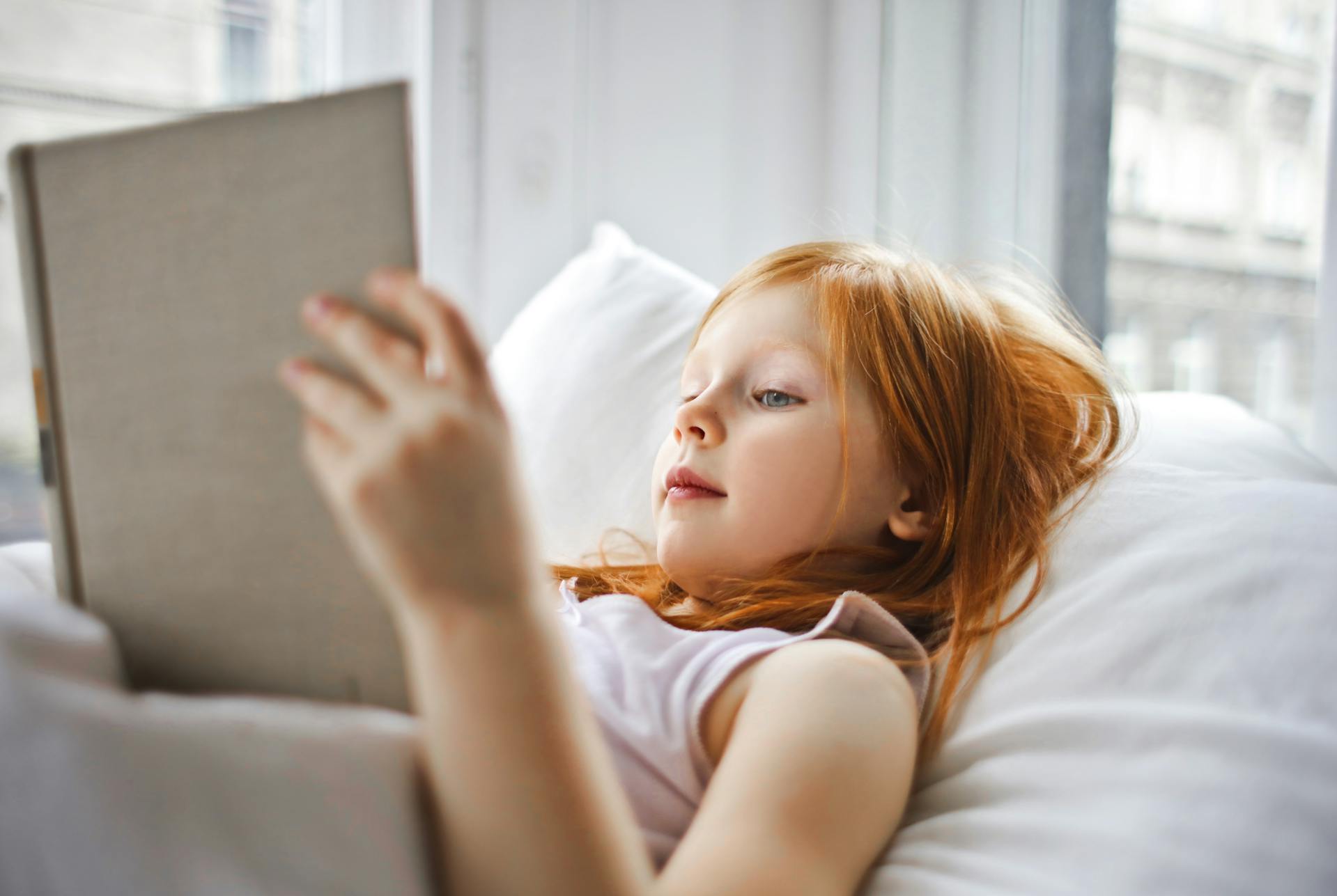 Ein kleines Mädchen hält ein Buch im Bett | Quelle: Pexels