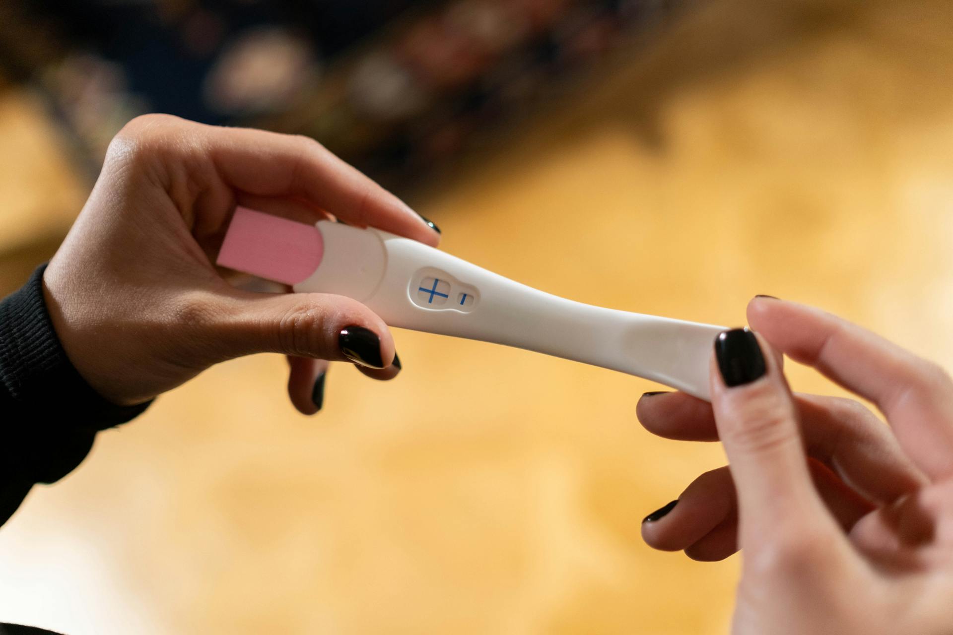 A woman holds a positive pregnancy test in her hand | Source: Pexels