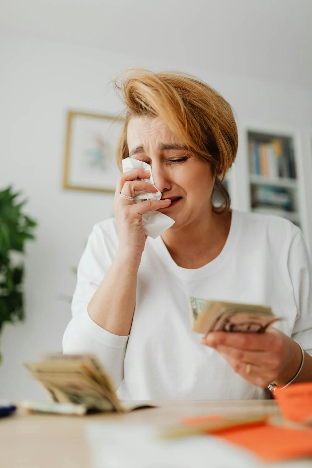 Eine weinende Frau mit Geld in der Hand | Quelle: Pexels