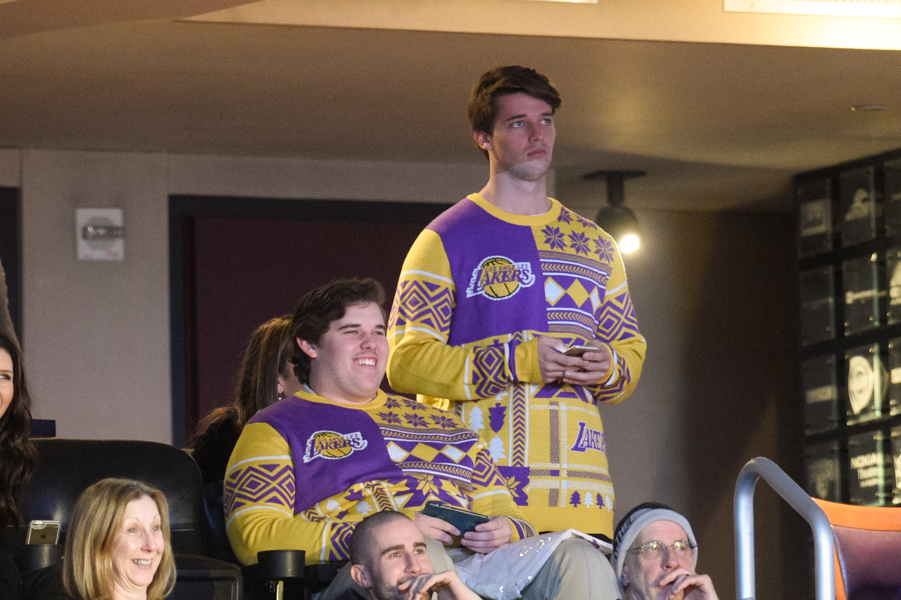 Christopher sieht sich im Dezember 2015 mit seinem Bruder Patrick das Spiel der Lakers im Staples Center in Los Angeles an. Bekleidet mit einem auffälligen lila-gelben Lakers-Pullover sitzt Christopher lächelnd da, die Haare ordentlich gekämmt und mit einer deutlich fülligeren Figur.