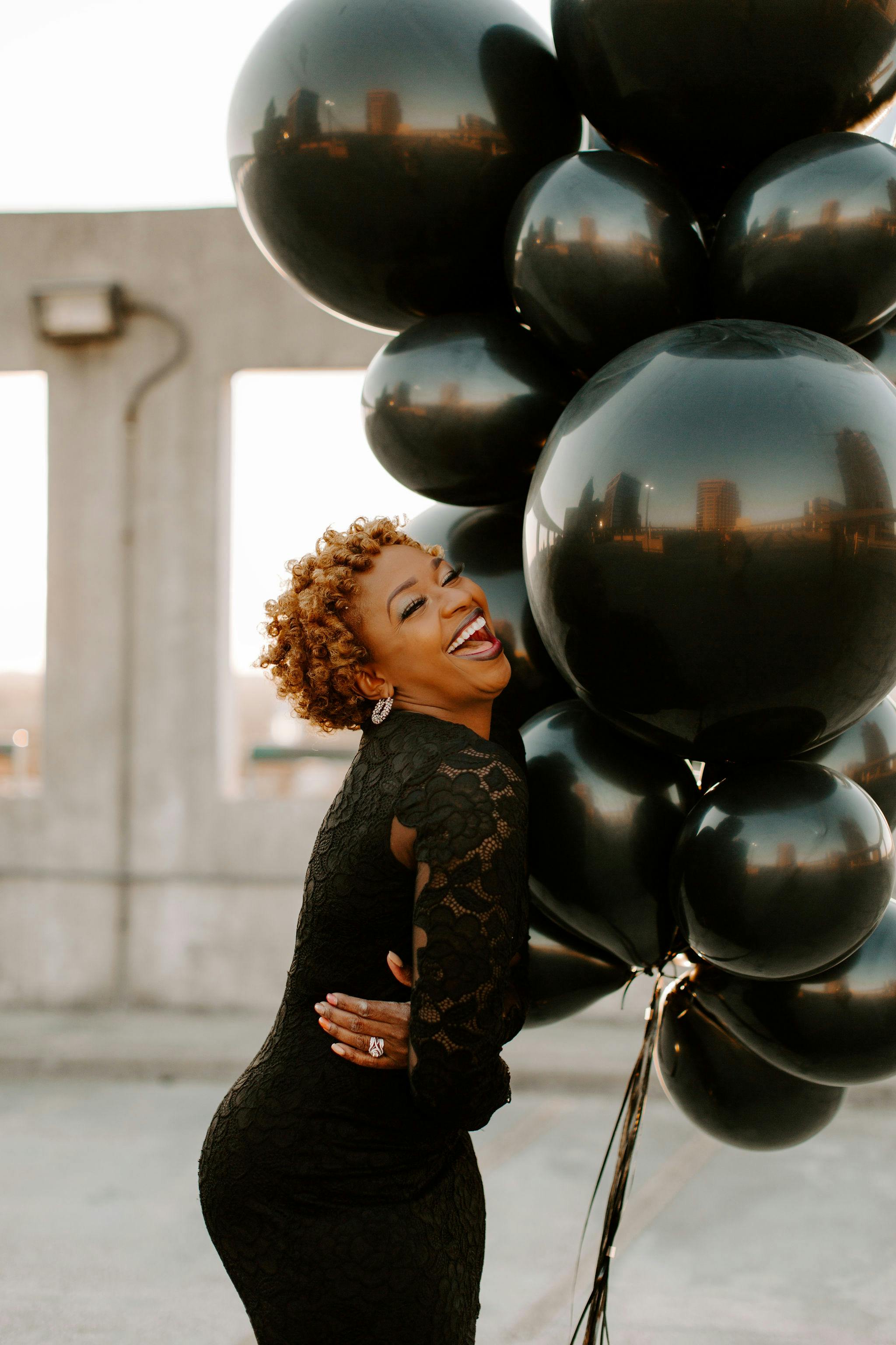 Eine Frau lacht, während sie Luftballons hält | Quelle: Pexels