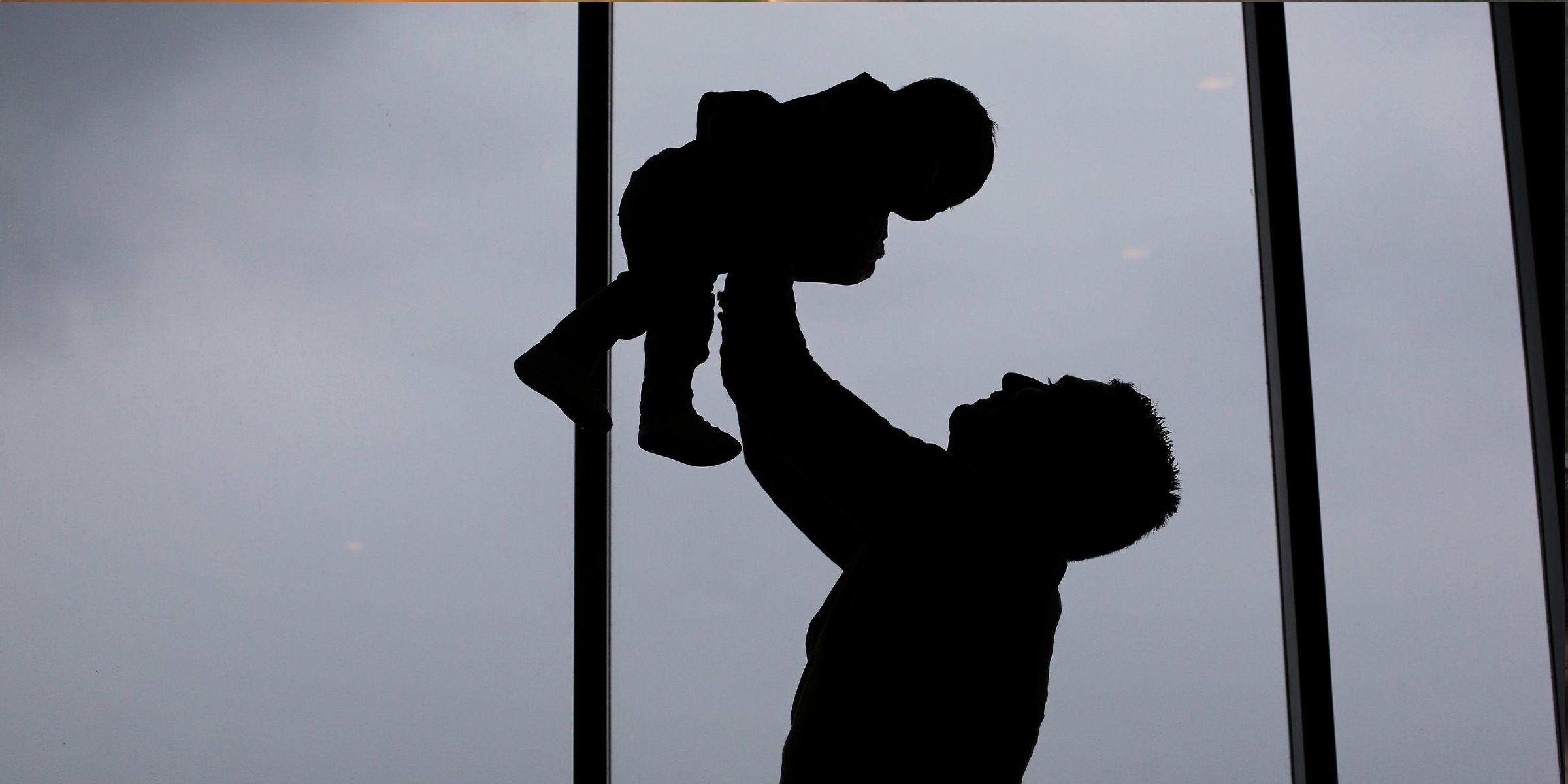 Silhouette eines Vaters und seines Babys zu Hause an einem bewölkten Tag | Quelle: Shutterstock