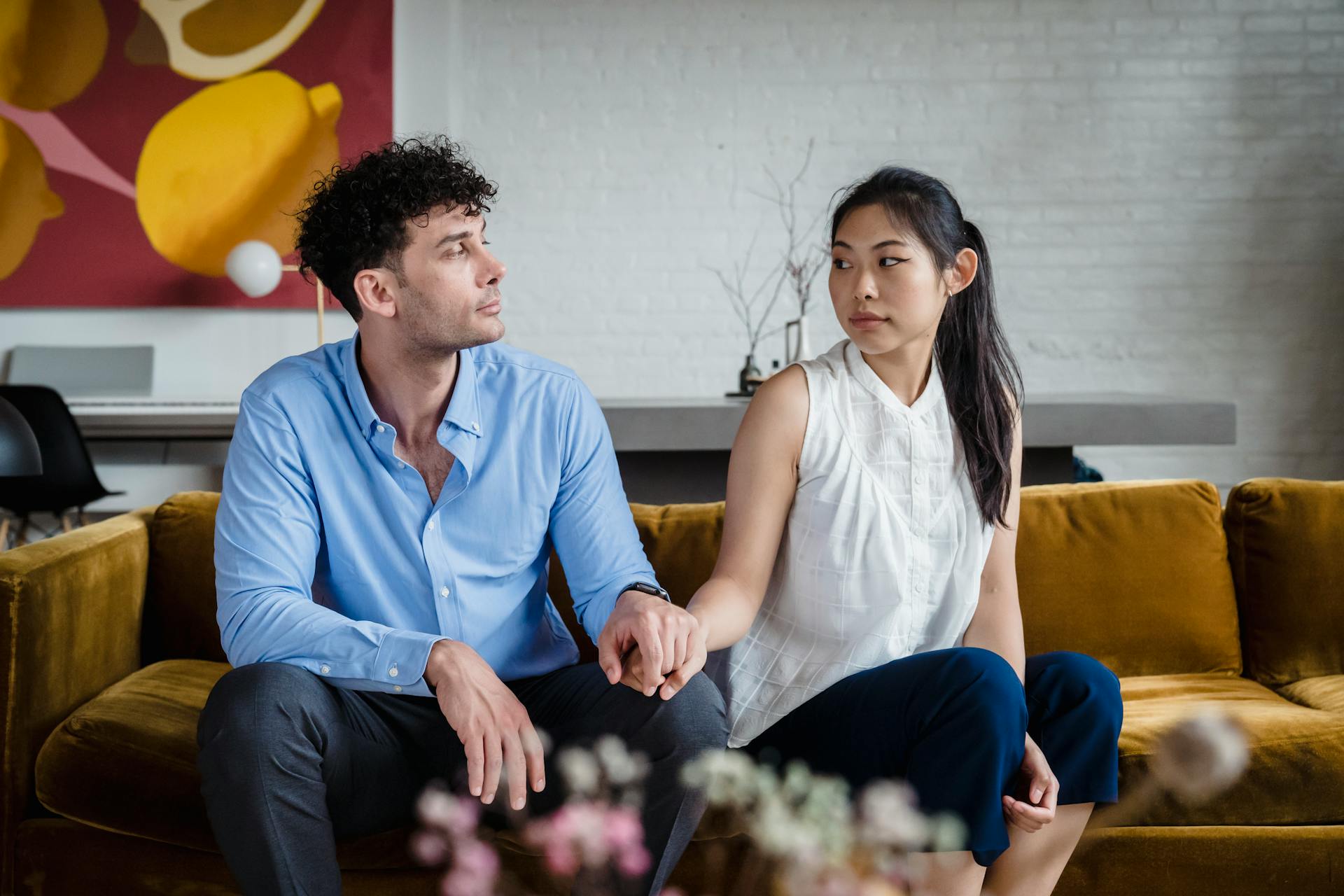 Ein besorgtes Paar hält sich an den Händen, während es auf einer Couch sitzt | Quelle: Pexels