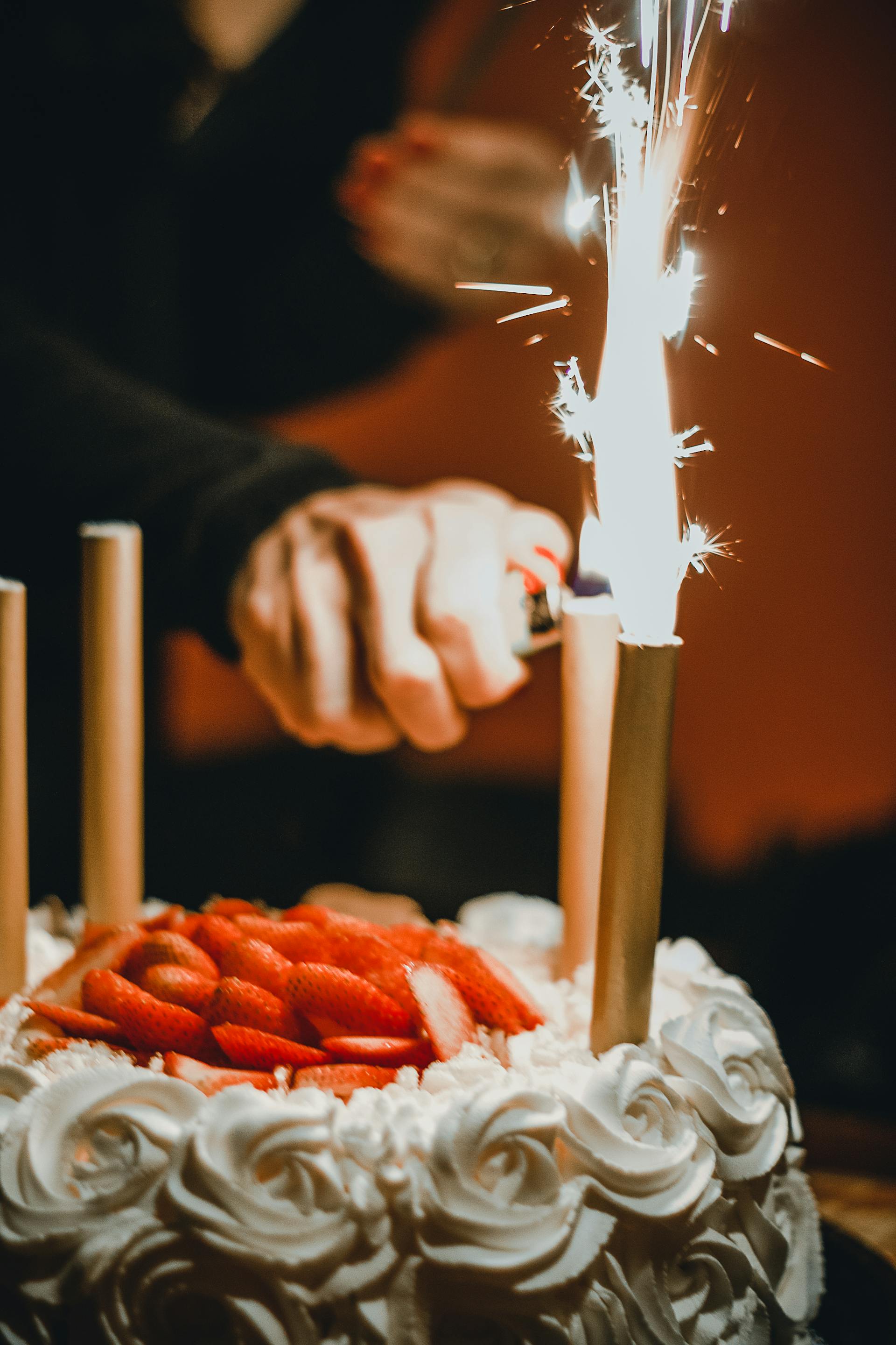 Eine Person zündet Wunderkerzen auf einer Torte an | Quelle: Pexels