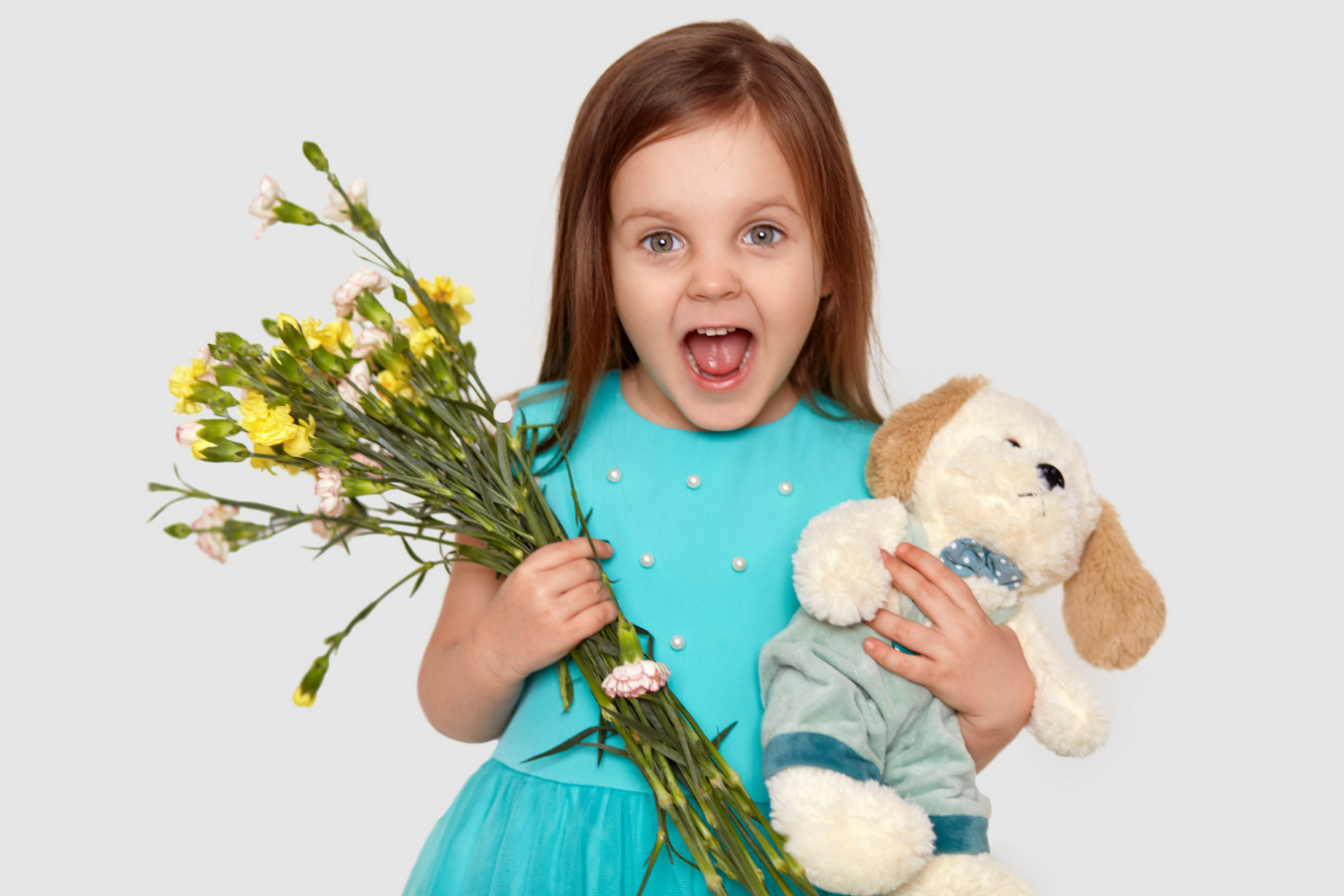 Ein erfreutes kleines Mädchen mit Blumen und einem Stofftier in der Hand | Quelle: Freepik