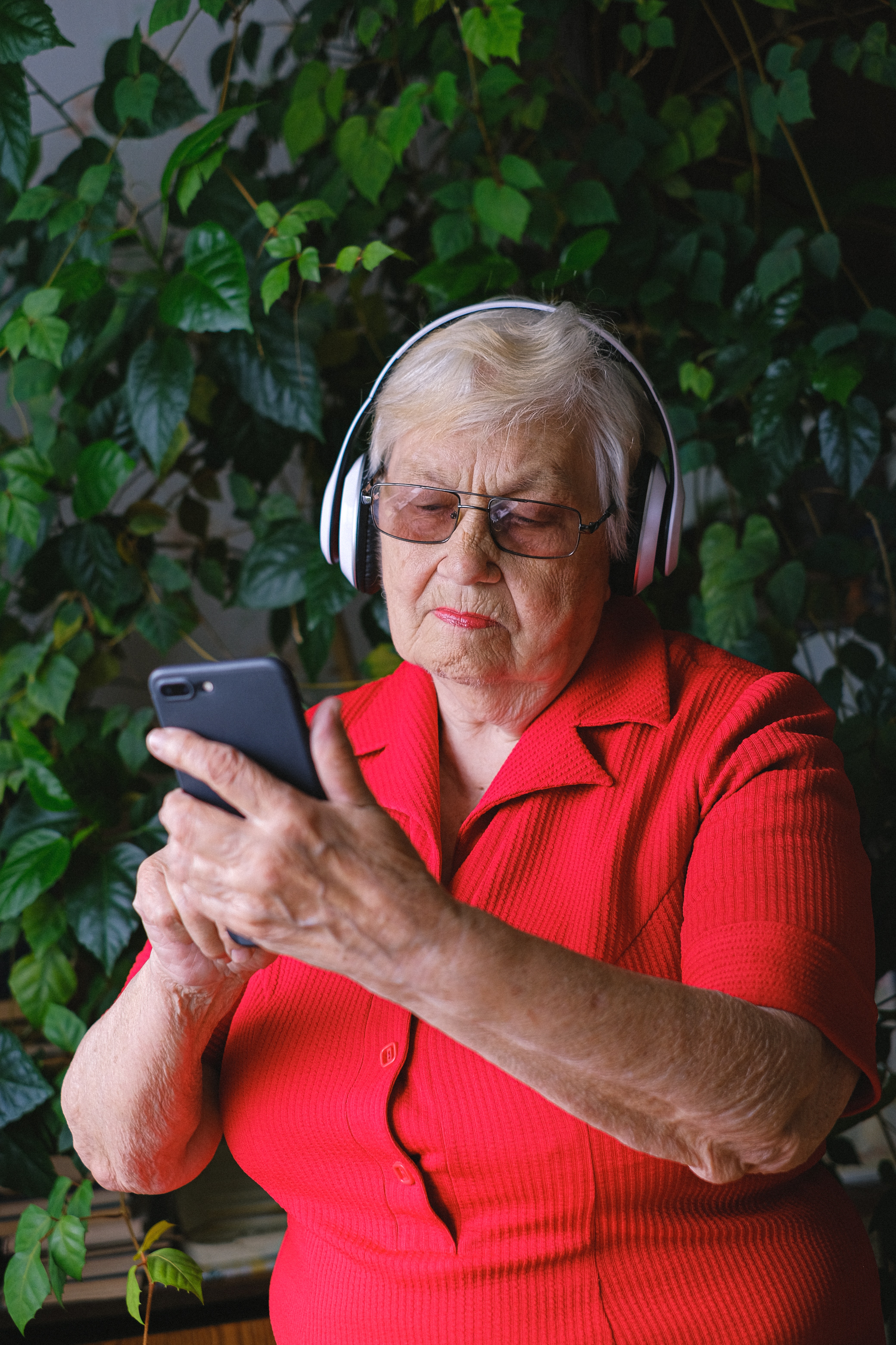 Eine ältere Frau trägt einen Kopfhörer und tippt auf einem Handy herum | Quelle: Pexels