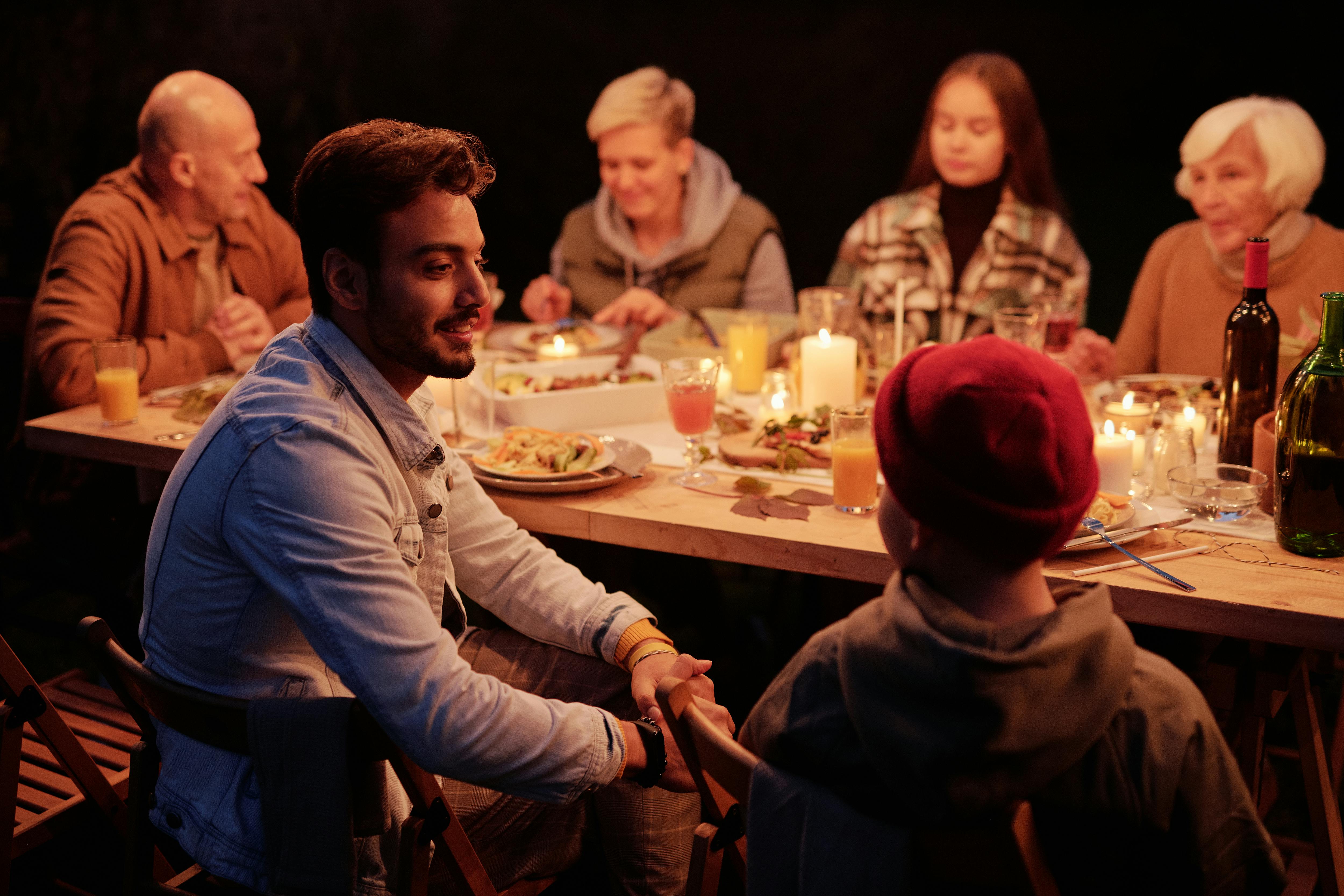 Menschen versammeln sich beim Abendessen im Nachtgarten und unterhalten sich | Quelle: Pexels