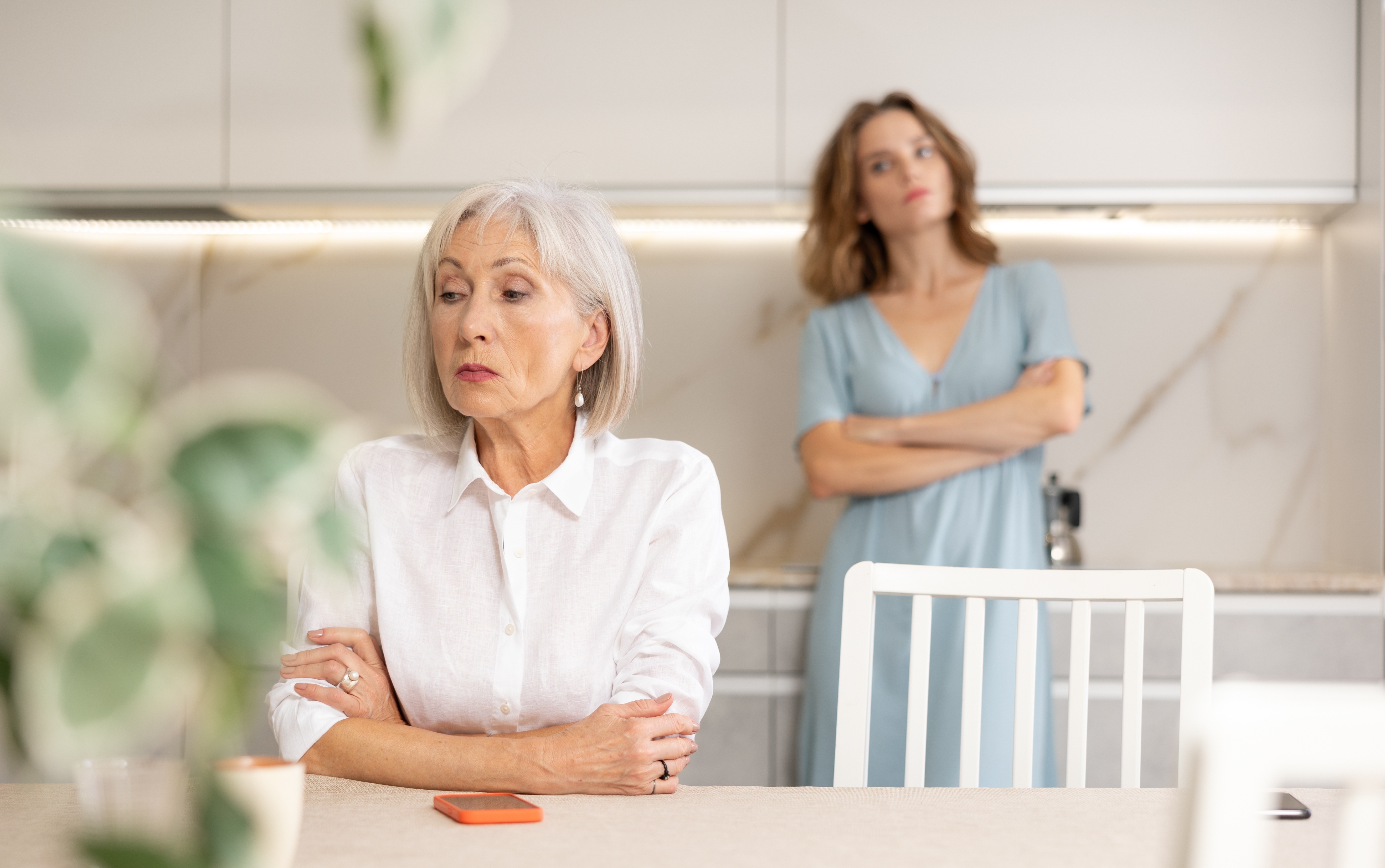 Eine ältere Frau sitzt mit verschränkten Armen nach einem Streit mit ihrer Schwiegertochter | Quelle: Shutterstock