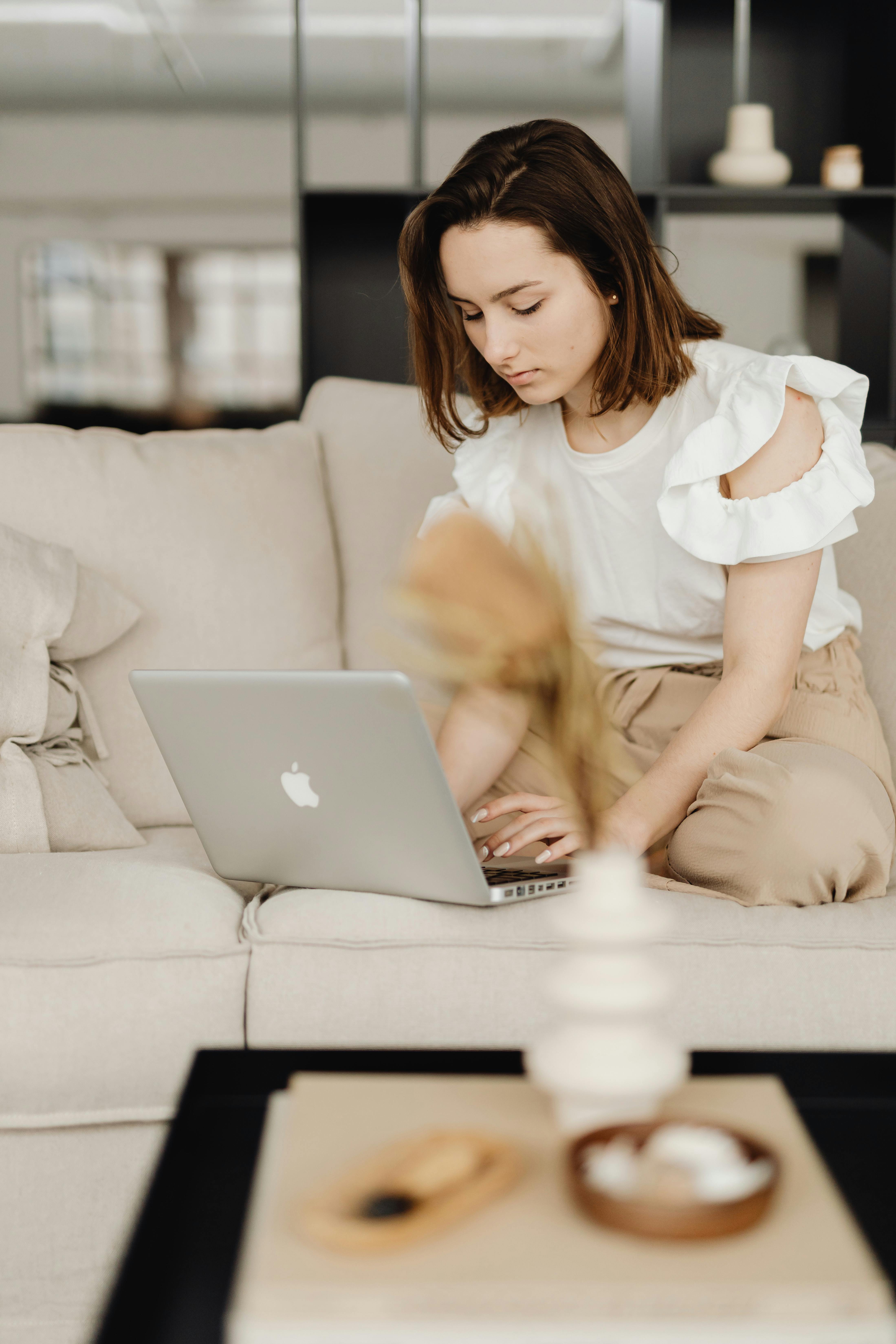Eine Frau auf der Couch, die auf einem Macbook tippt | Quelle: Pexels