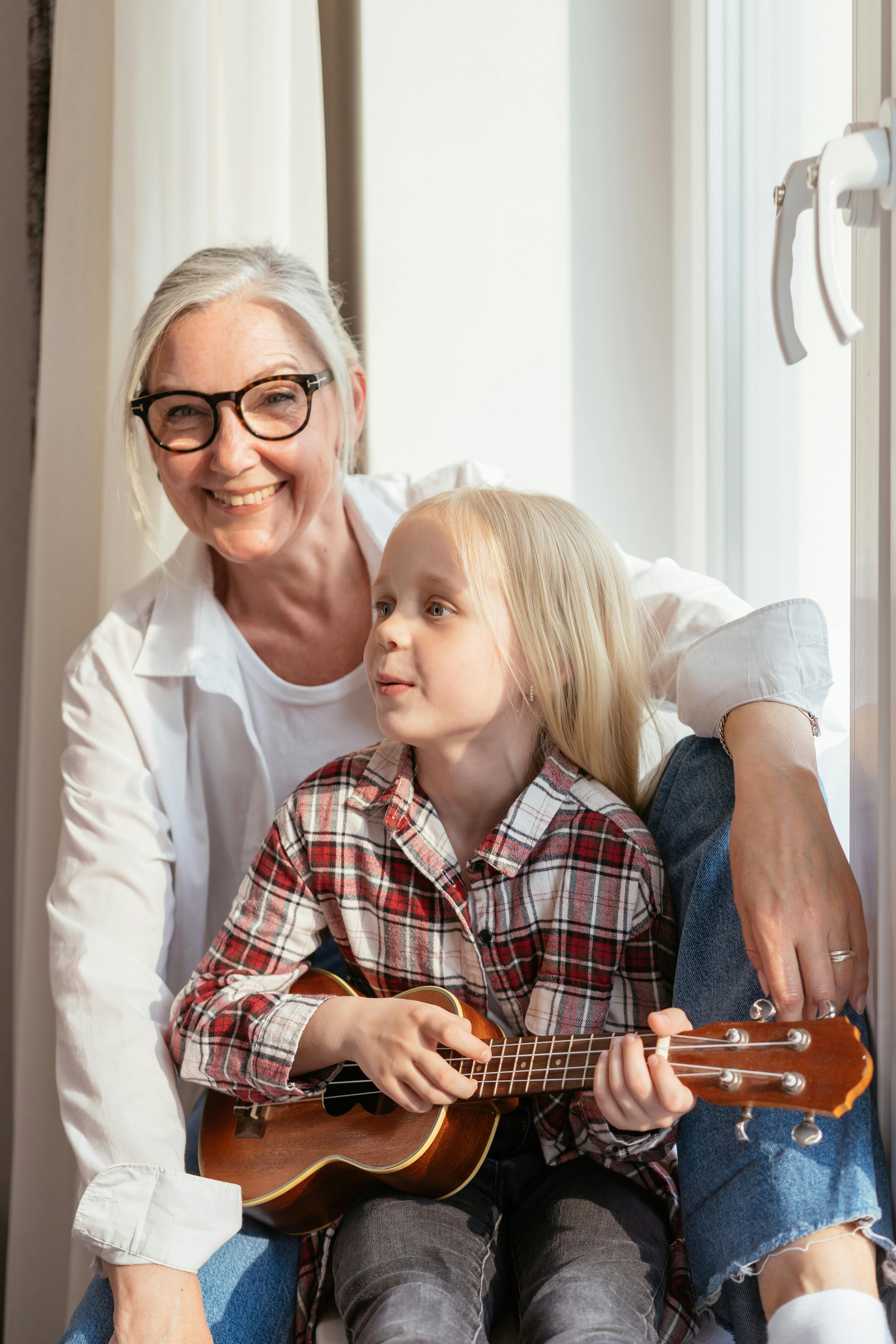 Eine Frau, die mit einem kleinen Mädchen, das eine Gitarre hält, zusammen ist | Quelle: Pexels