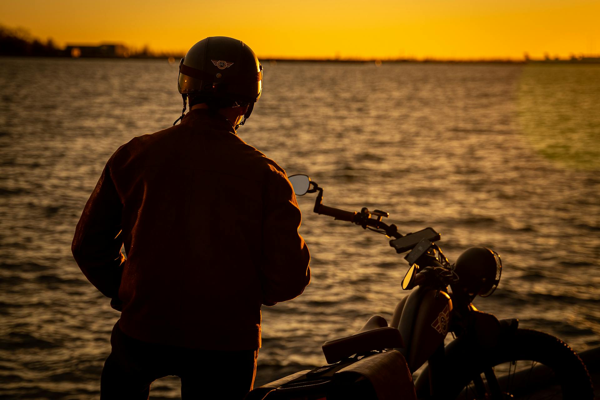 Silhouette eines Mannes, der am Ufer neben seinem Fahrrad steht | Quelle: Pexels