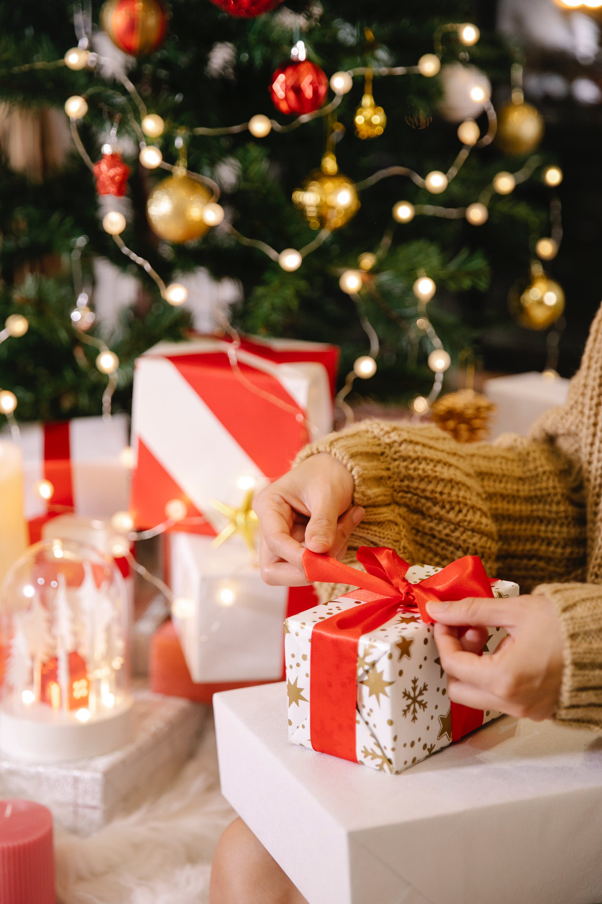Eine Frau packt ein Geschenkpaket in der Nähe eines Weihnachtsbaums ein | Quelle: Pexels