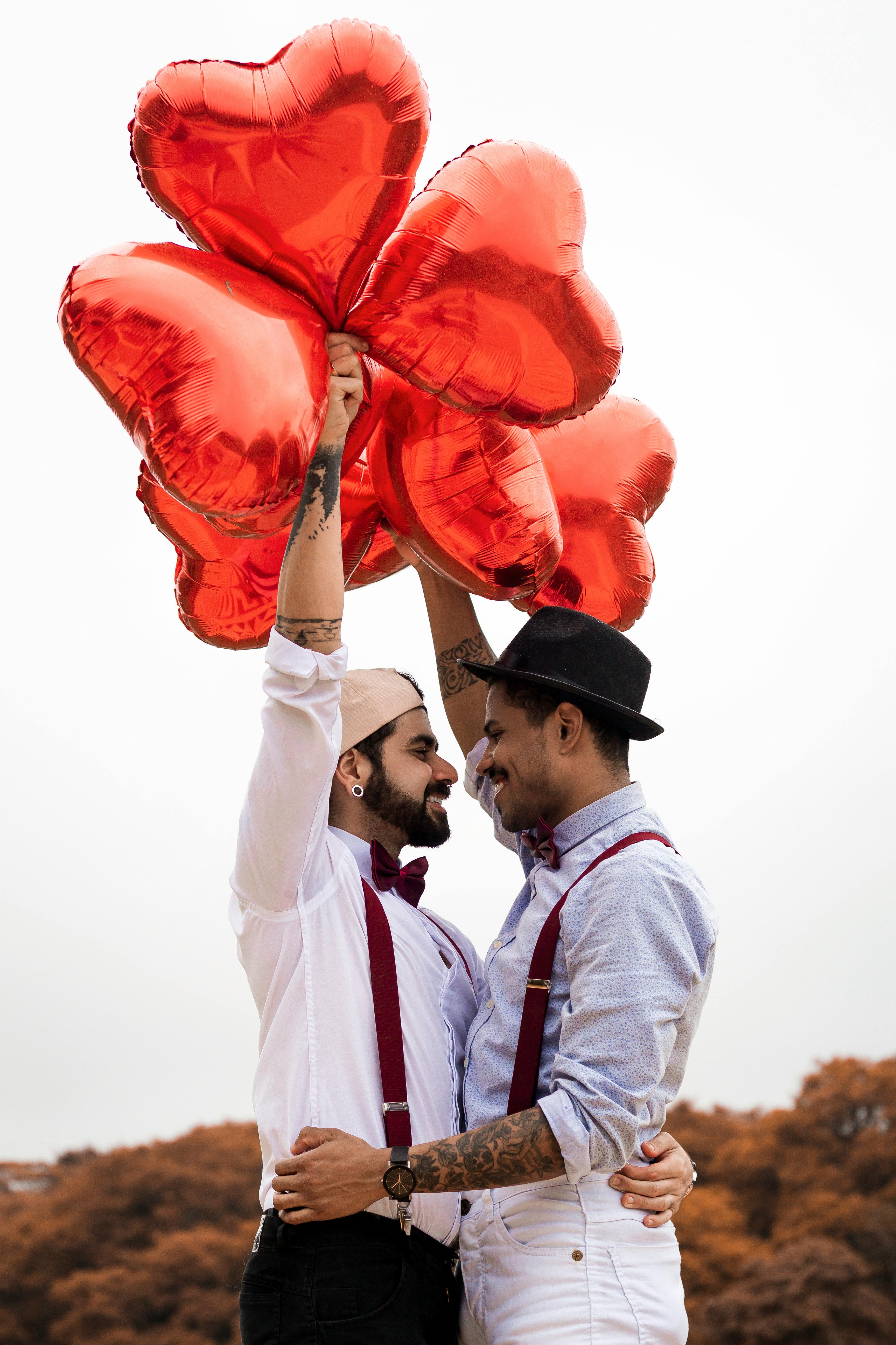 Zwei Männer umarmen sich, während sie Herzluftballons halten | Quelle: Pexels