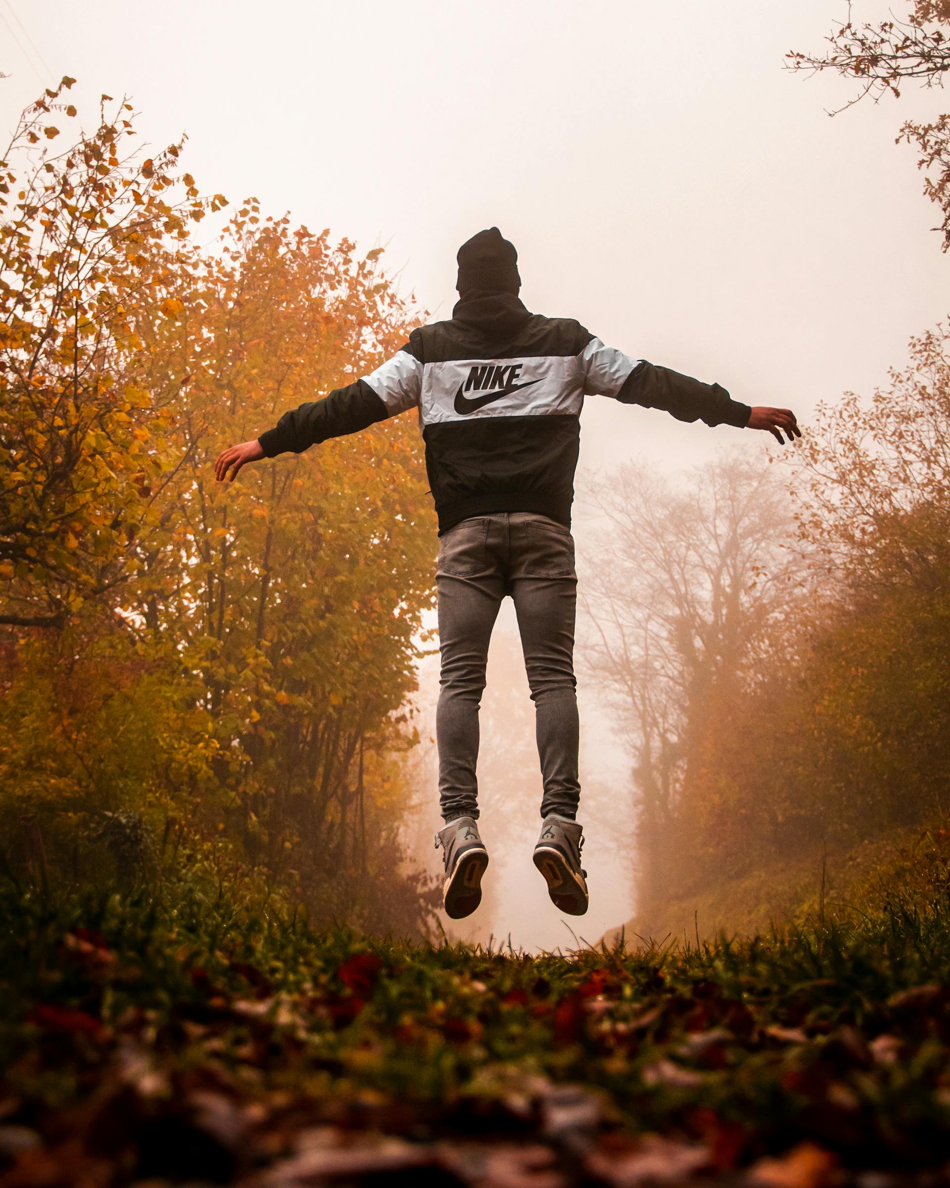 Ein Mann in einem Nike-Kapuzenpullover und einer grauen Hose springt in die Luft | Quelle: Pexels