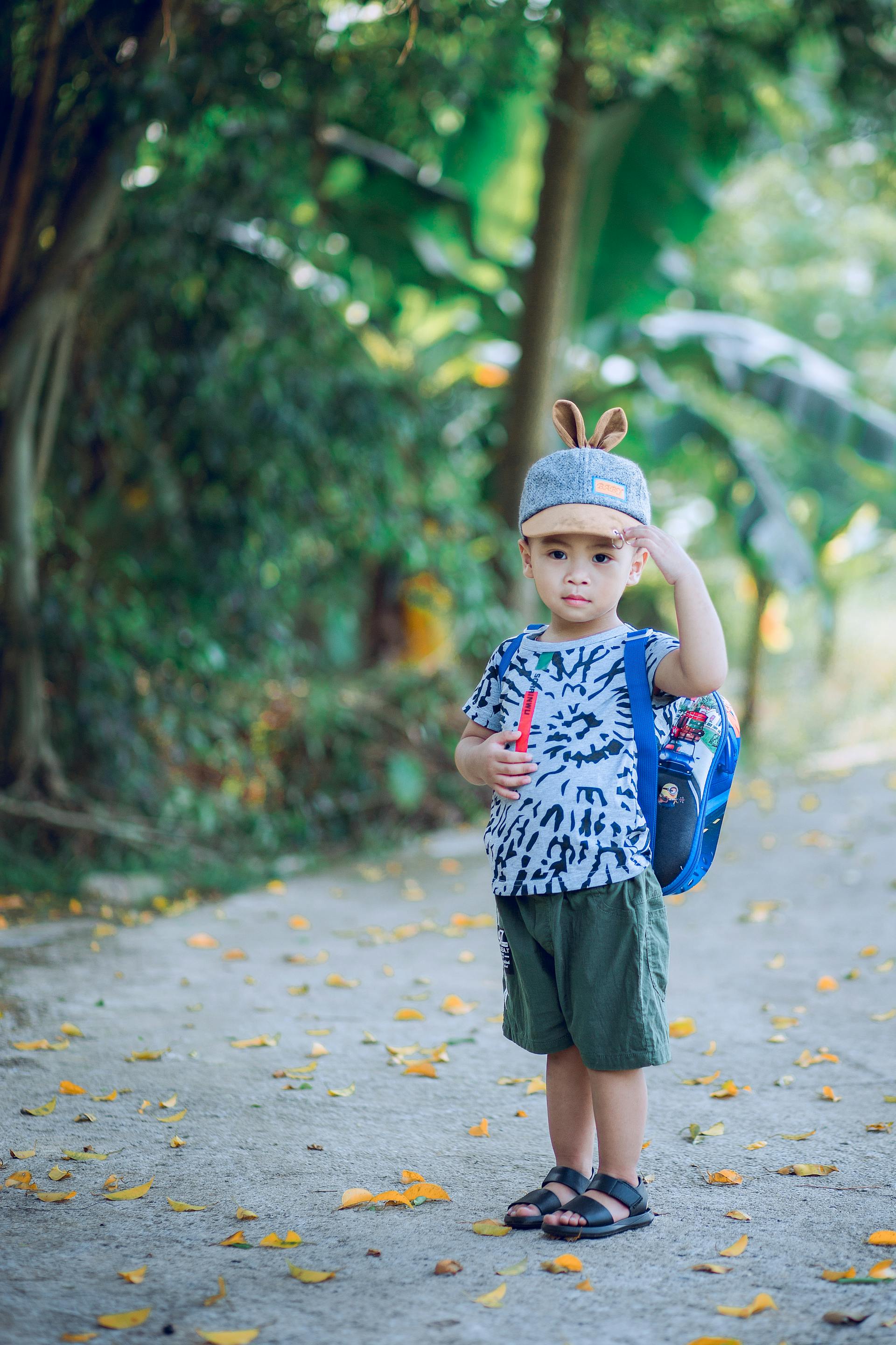 Ein kleiner Junge trägt einen Rucksack und einen Hut mit Tierohren | Quelle: Pexels